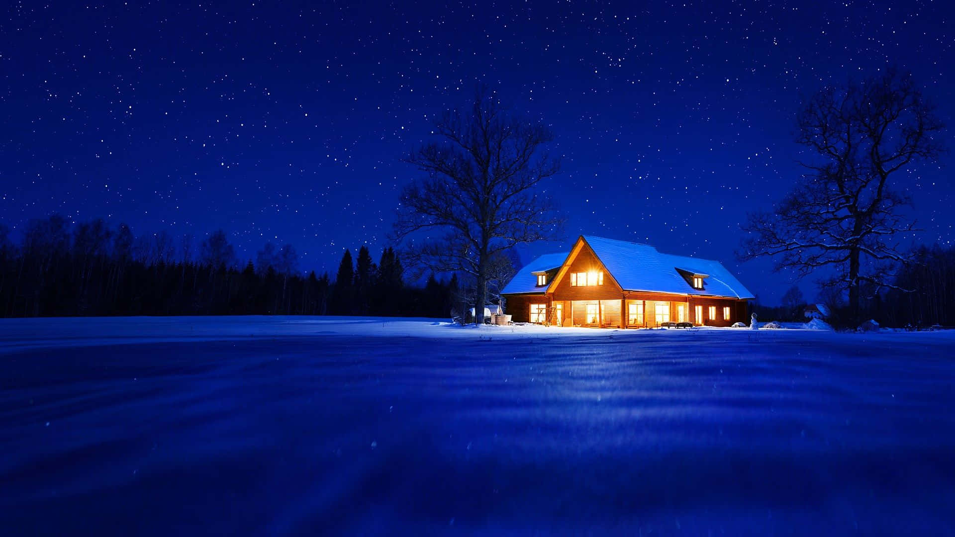 Cozy Winter Cabin 桌布 壁紙 — 一間舒適的木屋，窗戶透出溫暖的光芒，獨自坐落在雪地上，上方是繁星點點的夜空。