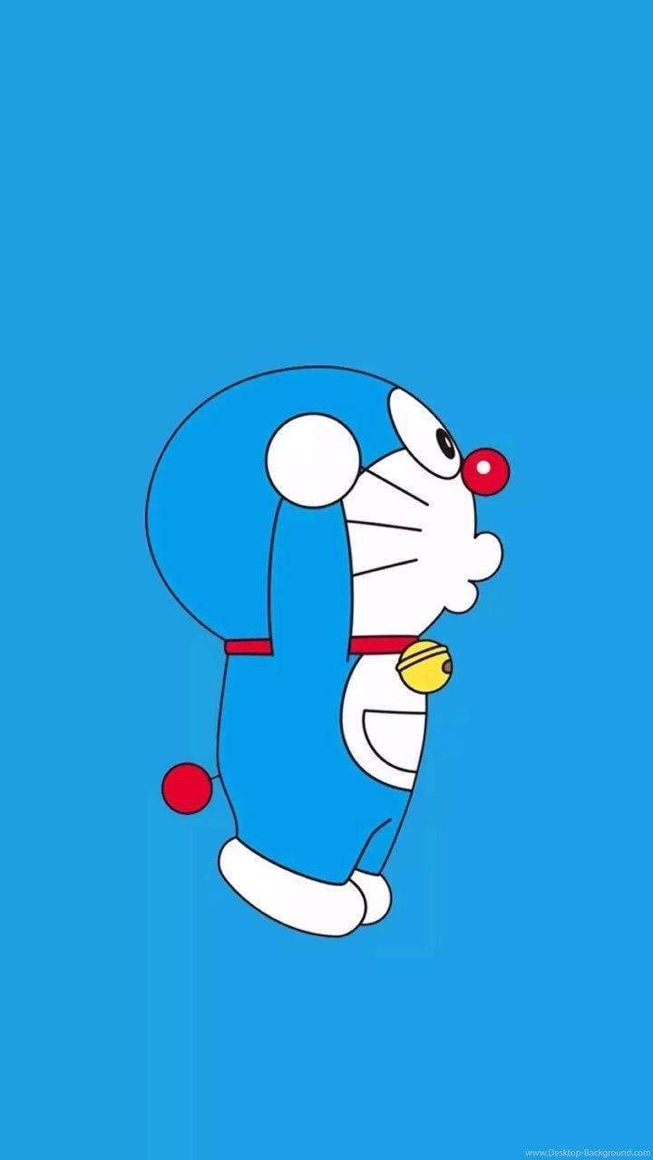 Doraemon 桌布 壁紙 — 一隻卡通機械貓，藍色身體、白色臉、紅色鼻子和鈴鐺，站在純藍色背景前。