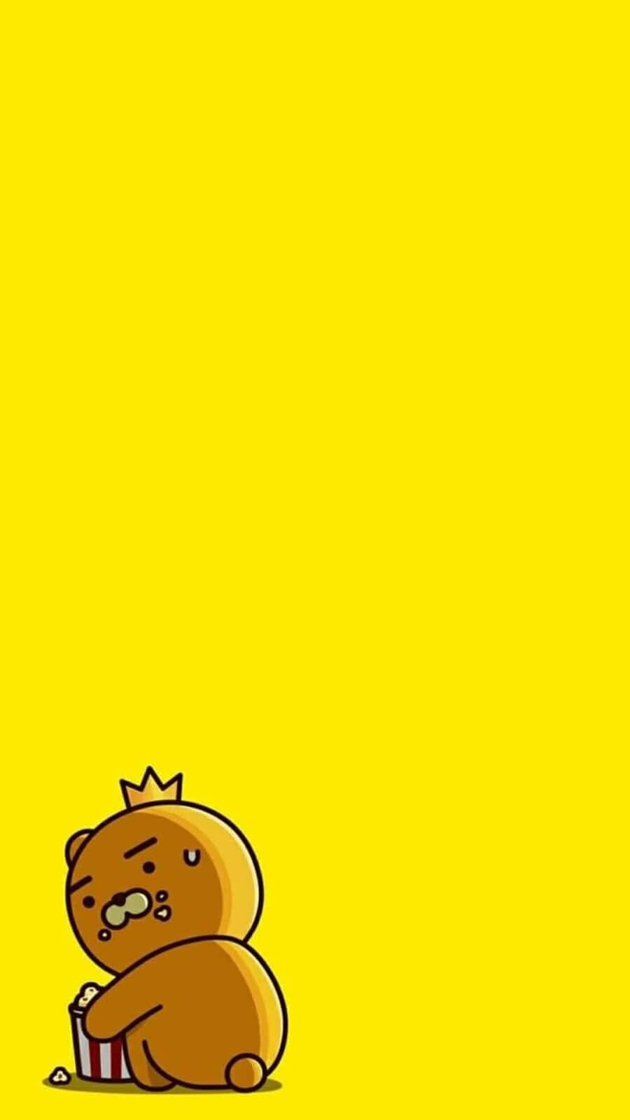 Kawaii Bear 桌布 壁紙 — 一隻可愛的棕色小熊戴著小皇冠，坐在明亮的黃色背景底部，帶著睡眼惺忪的表情吃爆谷。