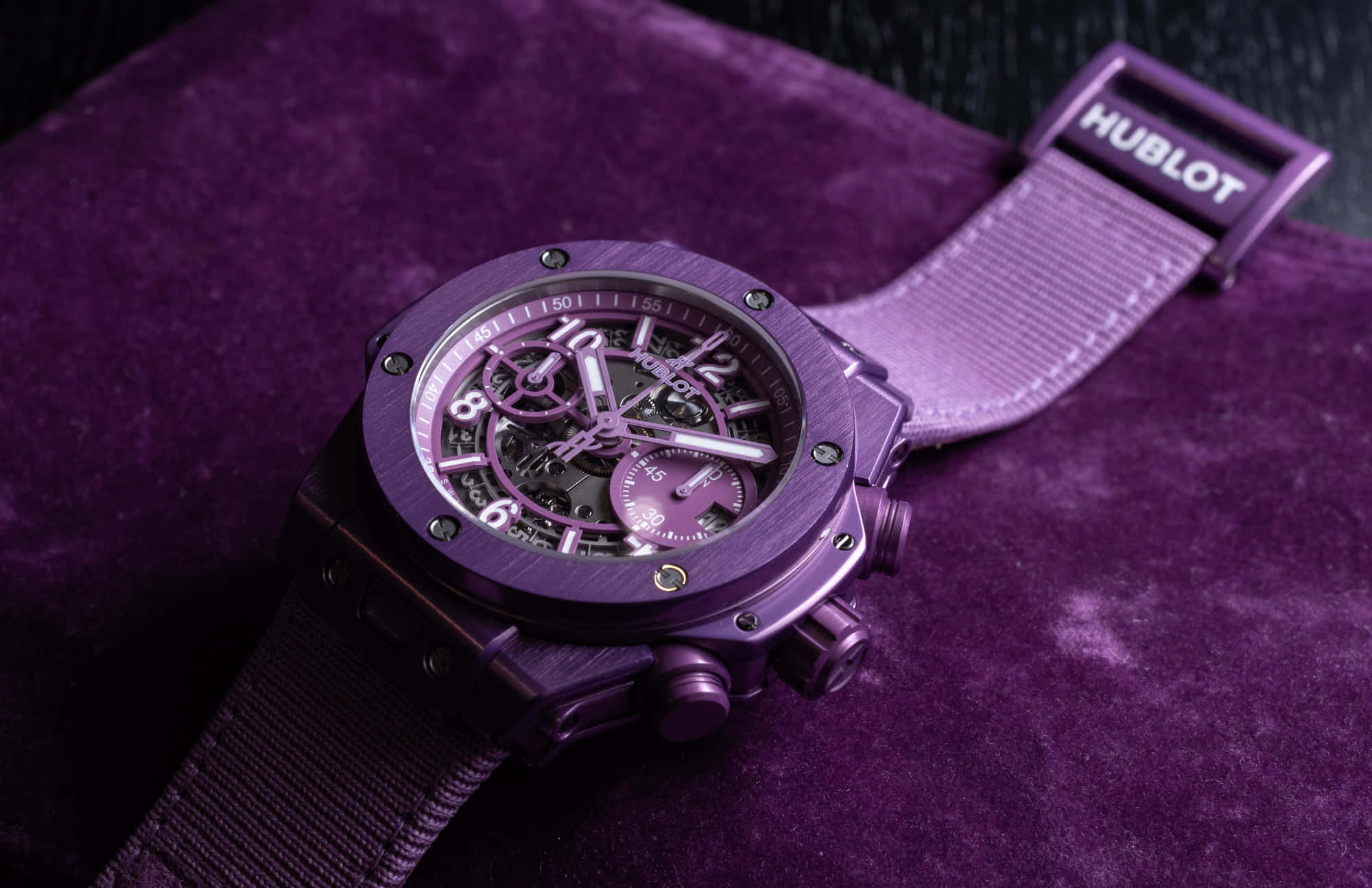 Purple Watch 桌布 壁紙 — 一隻奢華的紫色Hublot鏤空錶盤手錶優雅地放置在相配的天鵝絨表面上。