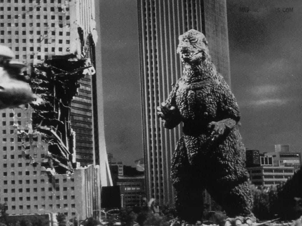 Classic Godzilla 桌布 壁紙 — 一隻巨型怪物站在破碎的摩天大樓之間，黑白城市景觀中，碎片飛揚，牠正在咆哮。