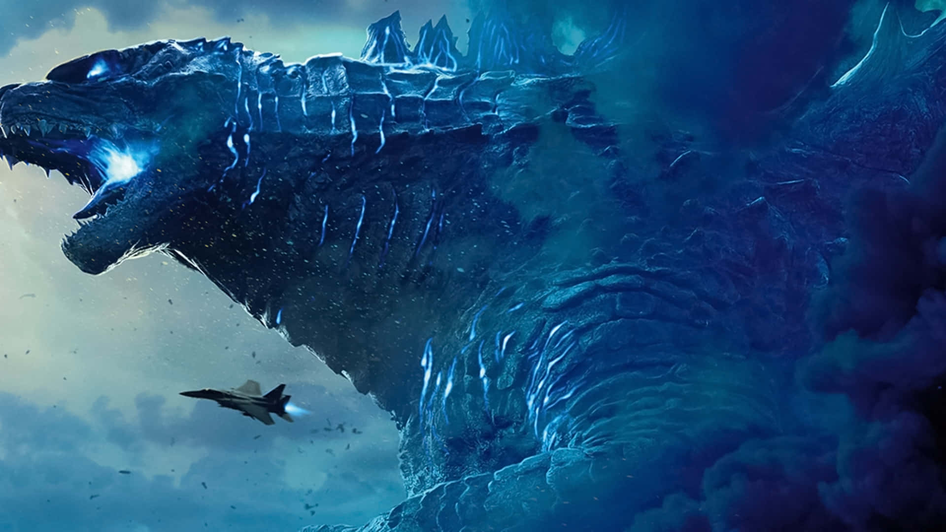 Godzilla City Destruction 桌布 壁紙 — 一隻巨大嘅冰封哥斯拉喺暴風雨中喺戰鬥機上空咆哮，散發出藍色光芒嘅能量。