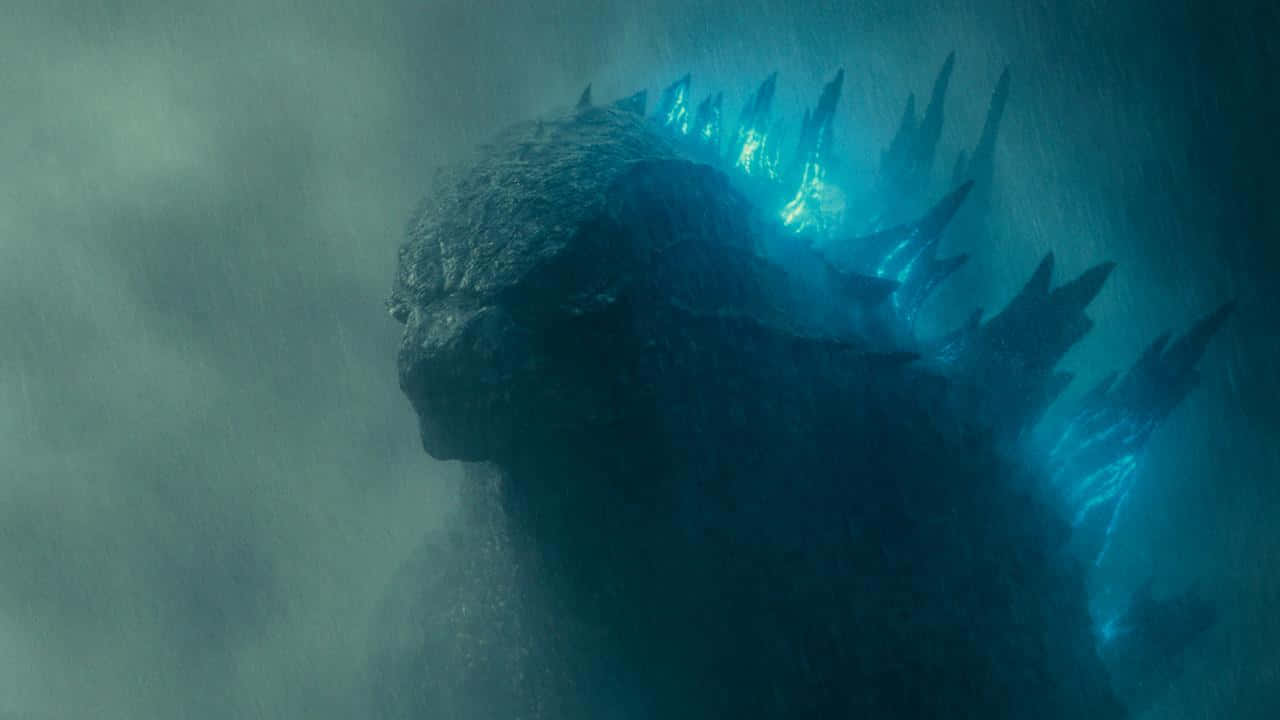 Burning Godzilla 桌布 壁紙 — 一隻巨大的哥斯拉從渾濁的水中浮現，發光的藍色背鰭劃破迷霧深處。