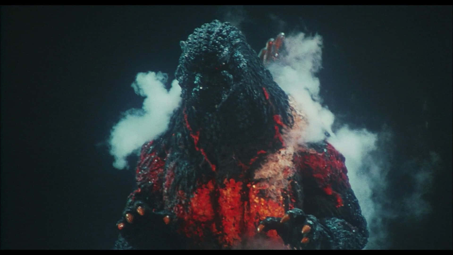 Godzilla 1954 桌布 壁紙 — 一隻巨大的哥斯拉從煙霧中出現，發光的紅色岩漿流過其燒焦的身體，背景漆黑。