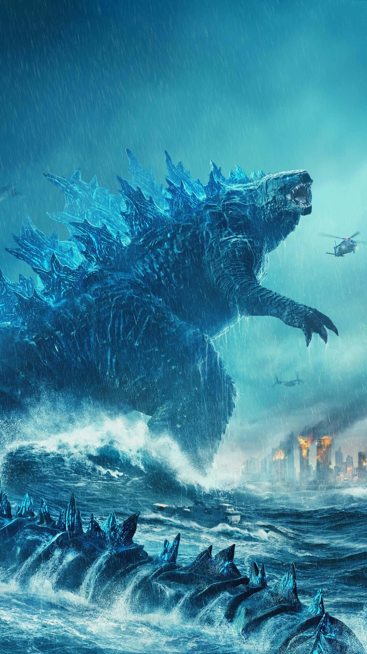 Classic Godzilla 桌布 壁紙 — 一隻巨大的藍色哥斯拉從暴風雨的海浪中出現，直升機在頭頂飛過，遠處是一座燃燒的城市。
