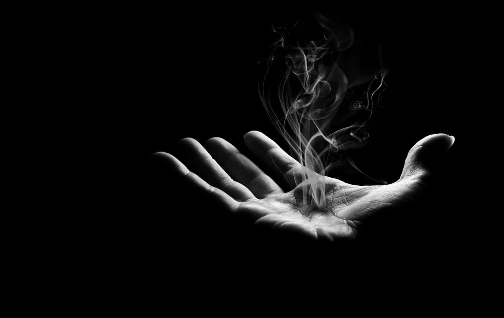 Dark Hand 桌布 壁紙 — 一隻張開的手在黑暗背景前托著上升煙霧的黑白照片。