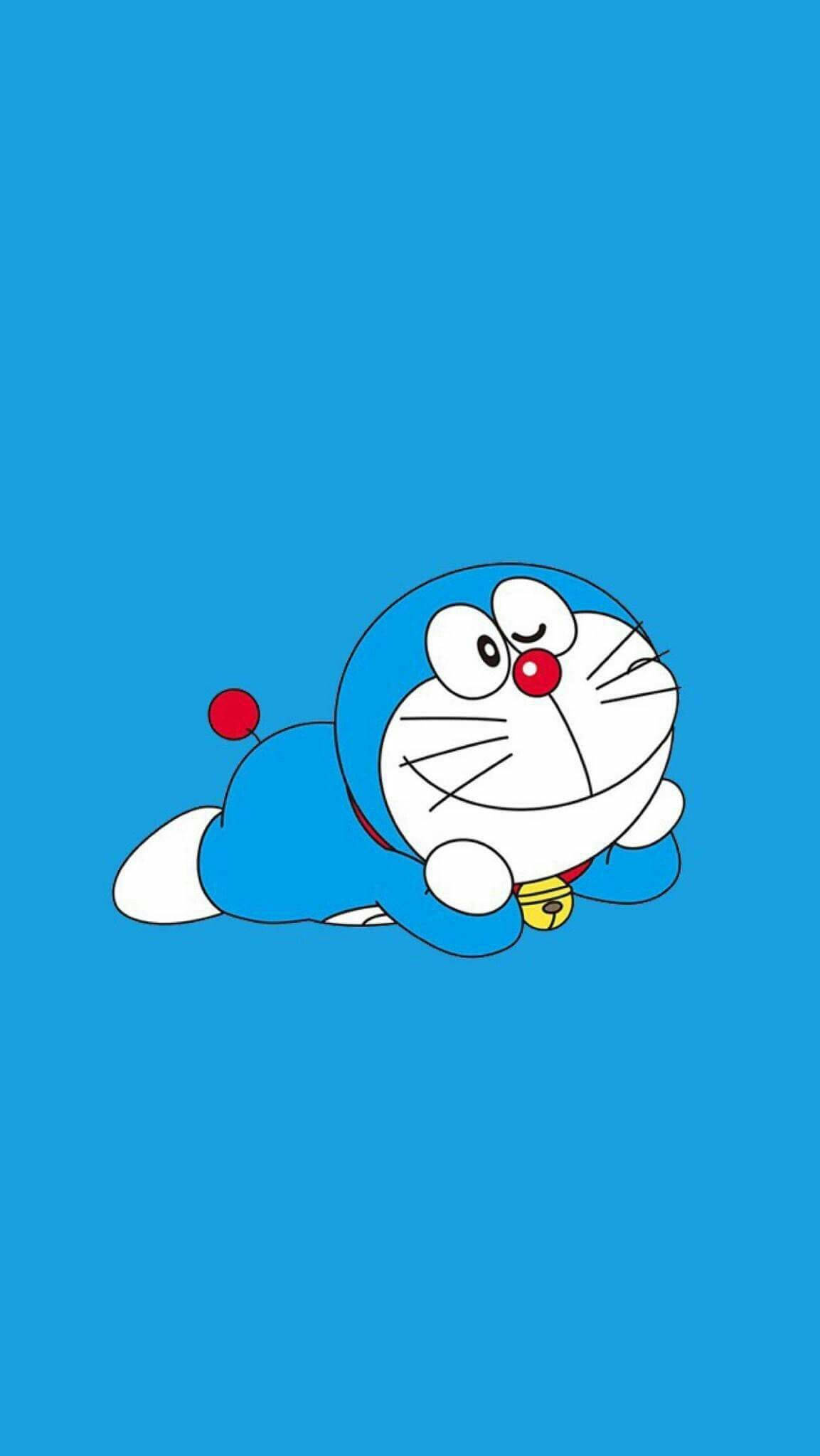 Doraemon 桌布 壁紙 — 一隻快樂的藍色機械貓，有紅色鼻子和鈴鐺，躺在純藍色背景上。