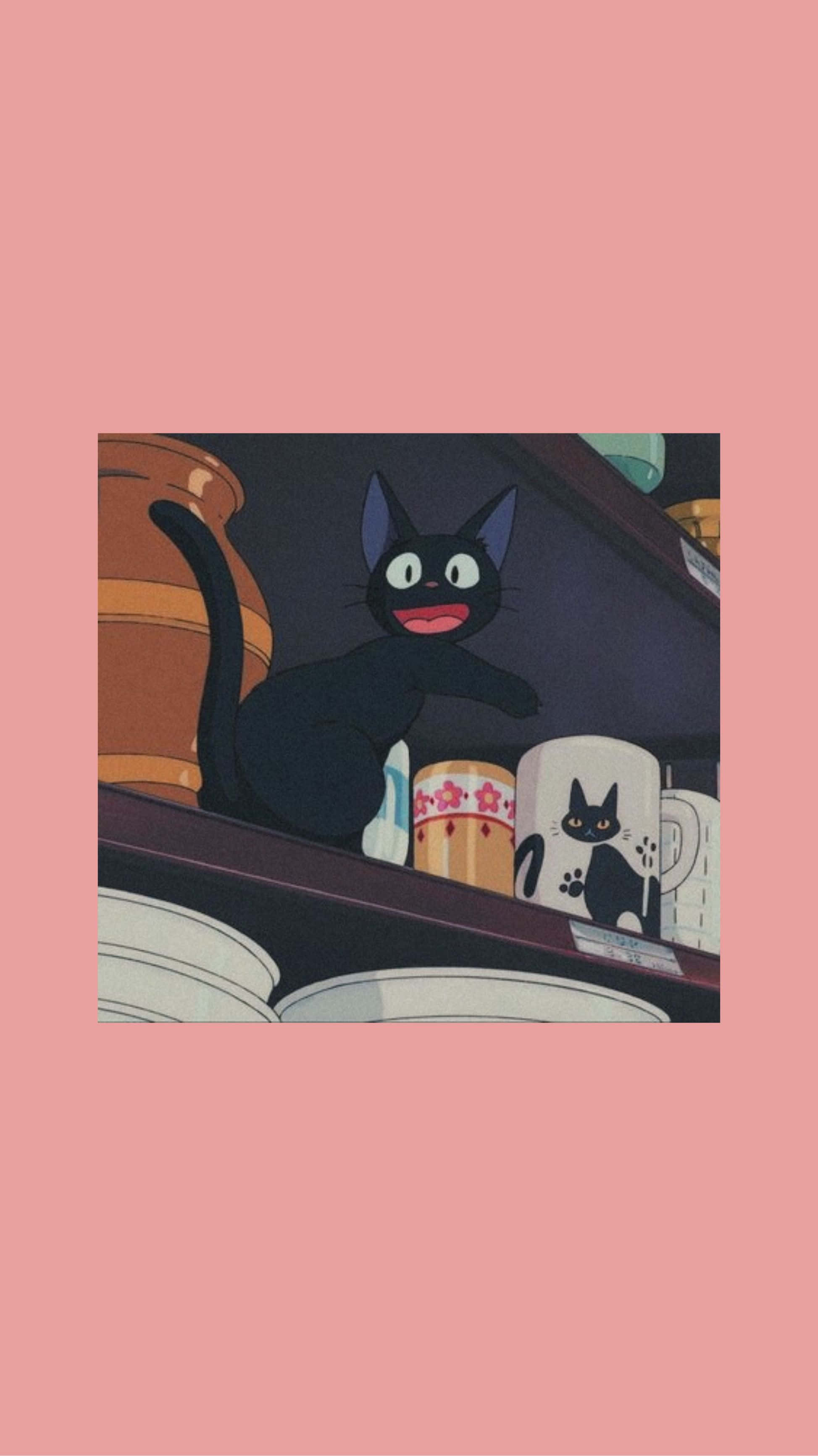 Jiji Cat 桌布 壁紙 — 一隻快樂的黑貓睜大眼睛，棲息在一個架子上，旁邊有杯子和陶器，背景是柔和的粉紅色。