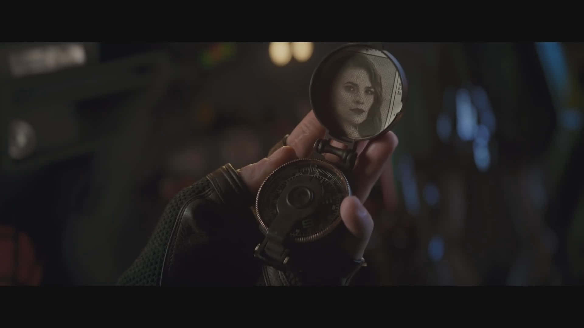 Peggy Carter 桌布 壁紙 — 一隻戴著手套的手拿著一個復古口袋鏡，在昏暗、陰鬱的環境中反射出一位女性的臉龐。