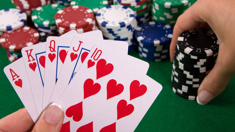 Poker 桌布 壁紙 — 一隻手喺綠色氈枱上揸住紅心同花順，周圍係色彩繽紛嘅籌碼。