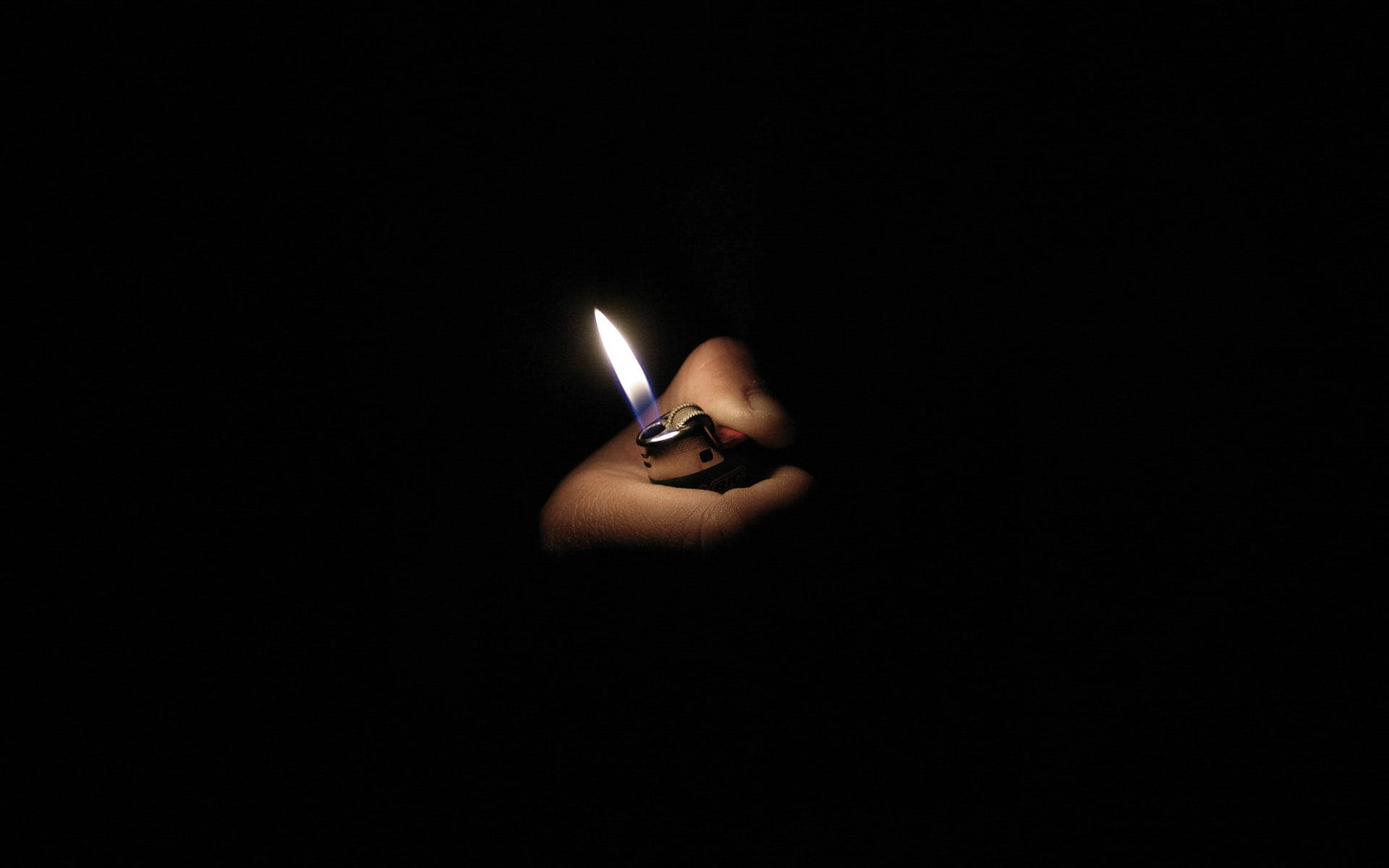 光 桌布 壁紙 — 一隻手在絕對黑暗中握著一個閃爍的打火機火焰，在皮膚上投射出柔和的光線。