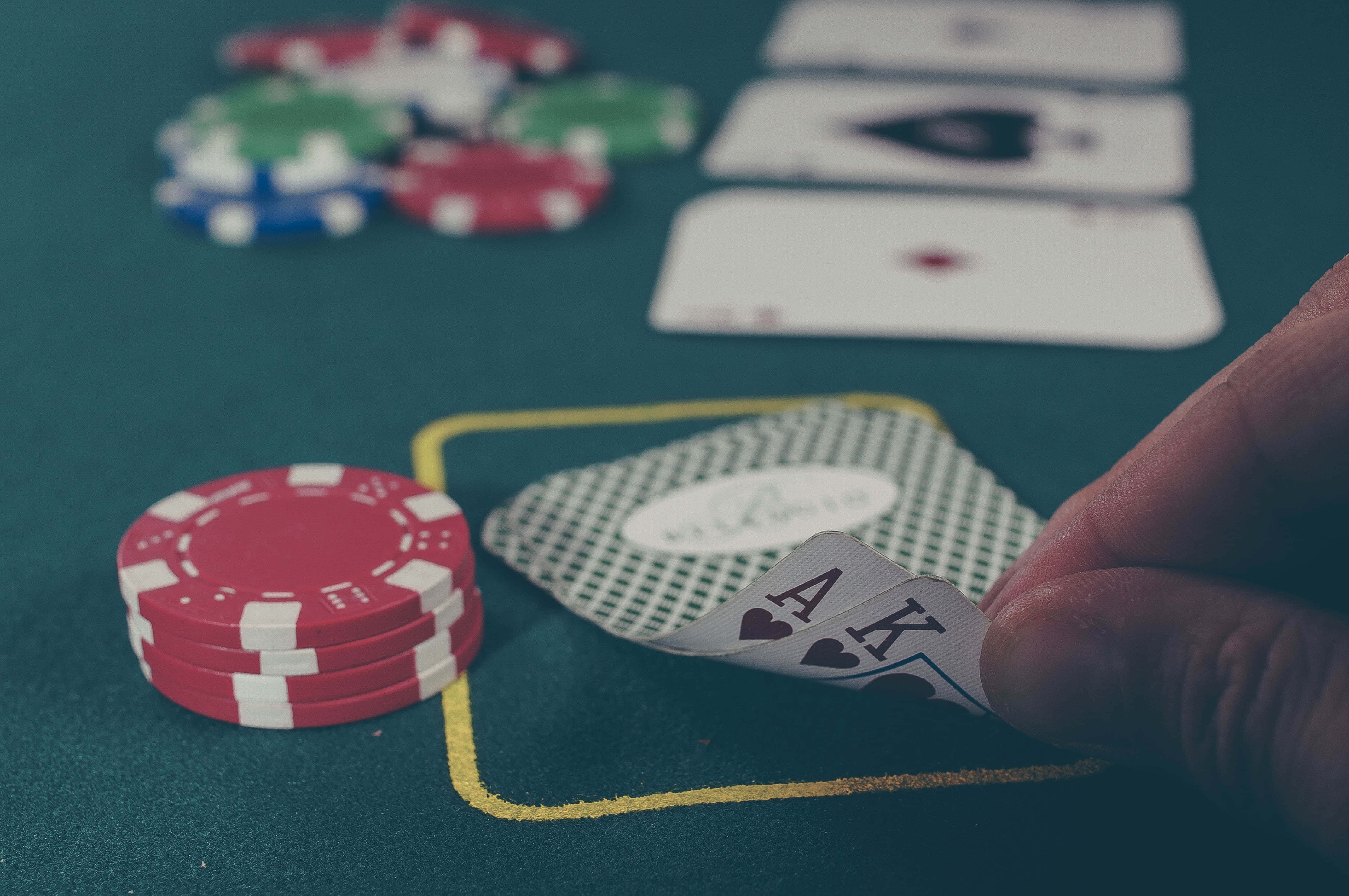 Poker Table 桌布 壁紙 — 一隻手在綠色賭桌上揭開一對Ace，周圍是色彩繽紛的籌碼和翻開的牌。