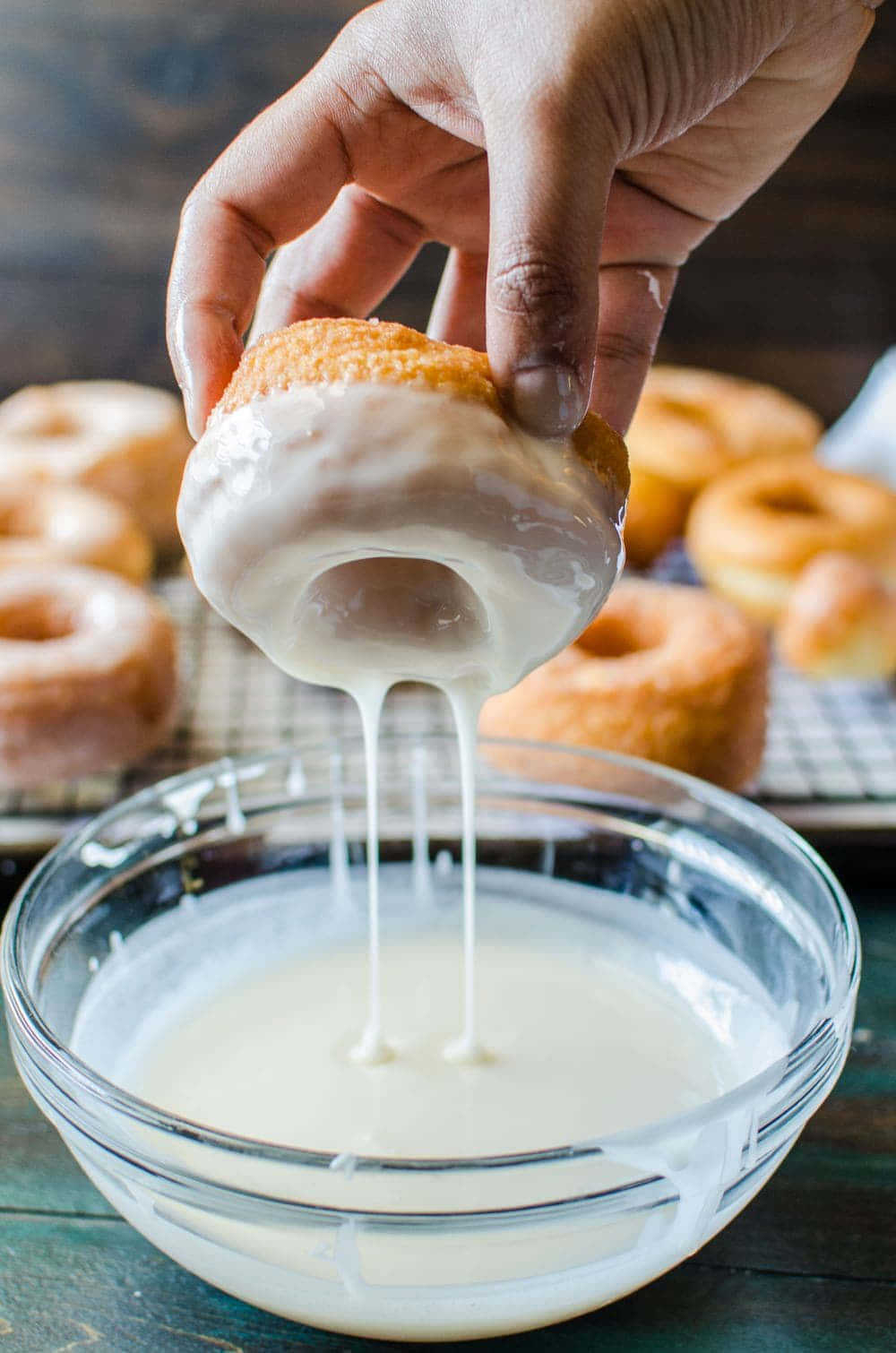Glazed Donut 桌布 壁紙 — 一隻手將一個金色冬甩浸入一碗奶油狀的白色糖霜中，濃稠的滴落物回落到碗中。
