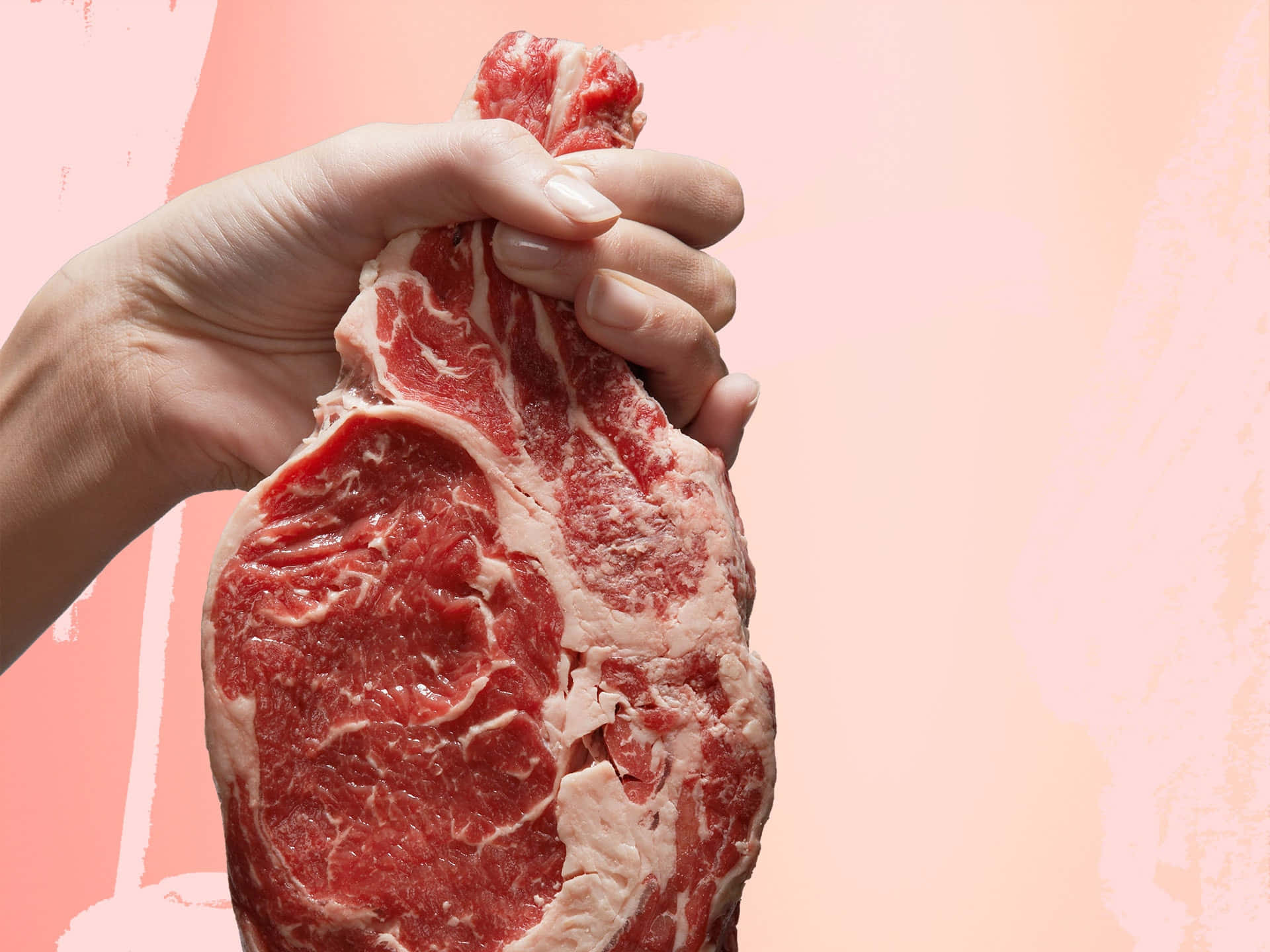 Red Meat 桌布 壁紙 — 一隻手抓住一塊帶有大理石花紋脂肪的生牛肉扒，背景是柔軟的粉紅色紋理。