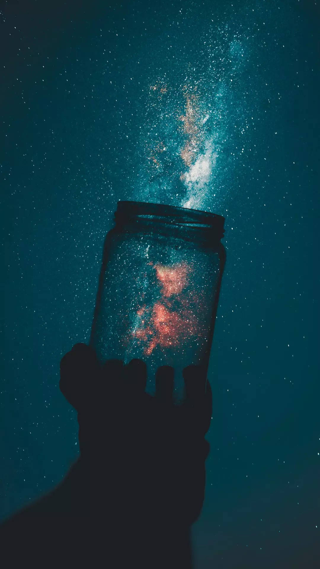銀河 桌布 壁紙 — 一隻手拿著一個罐子，從中一個充滿活力的星星和宇宙塵埃的星系灑落到深藍綠色的夜空中。
