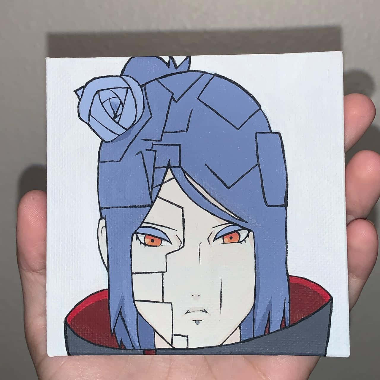 Akatsuki Drawing 桌布 壁紙 — 一隻手拿著一幅小型帆布畫，畫中是一個藍髮紅眼、身穿紅色斗篷的動漫角色。