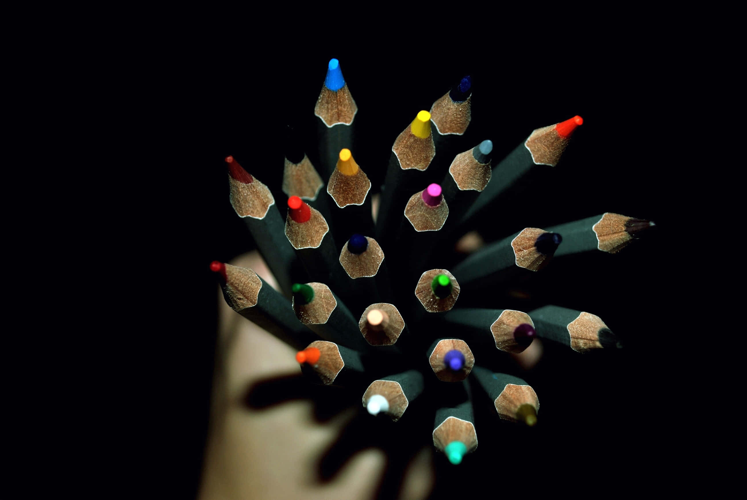 pencil 桌布 壁紙 — 一隻手拿著一束色彩繽紛的削尖鉛筆，背景是純黑色。