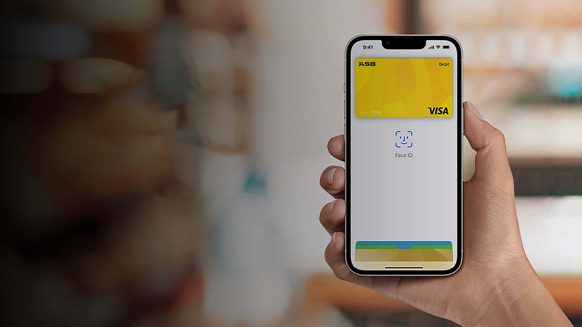 Apple Pay ASB Visa 壁紙 — 一隻手拿著智能手機，顯示一張黃色ASB Visa扣賬卡，Face ID掃描準備就緒。