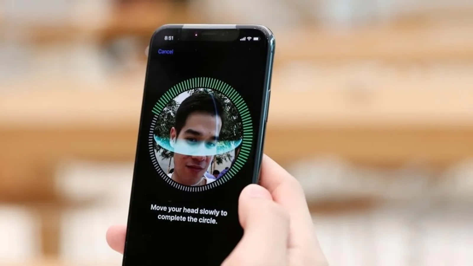 Face Id 桌布 壁紙 — 一隻手拿著智能手機，顯示面部識別設定畫面，一個人的臉在綠色掃描圓圈內。