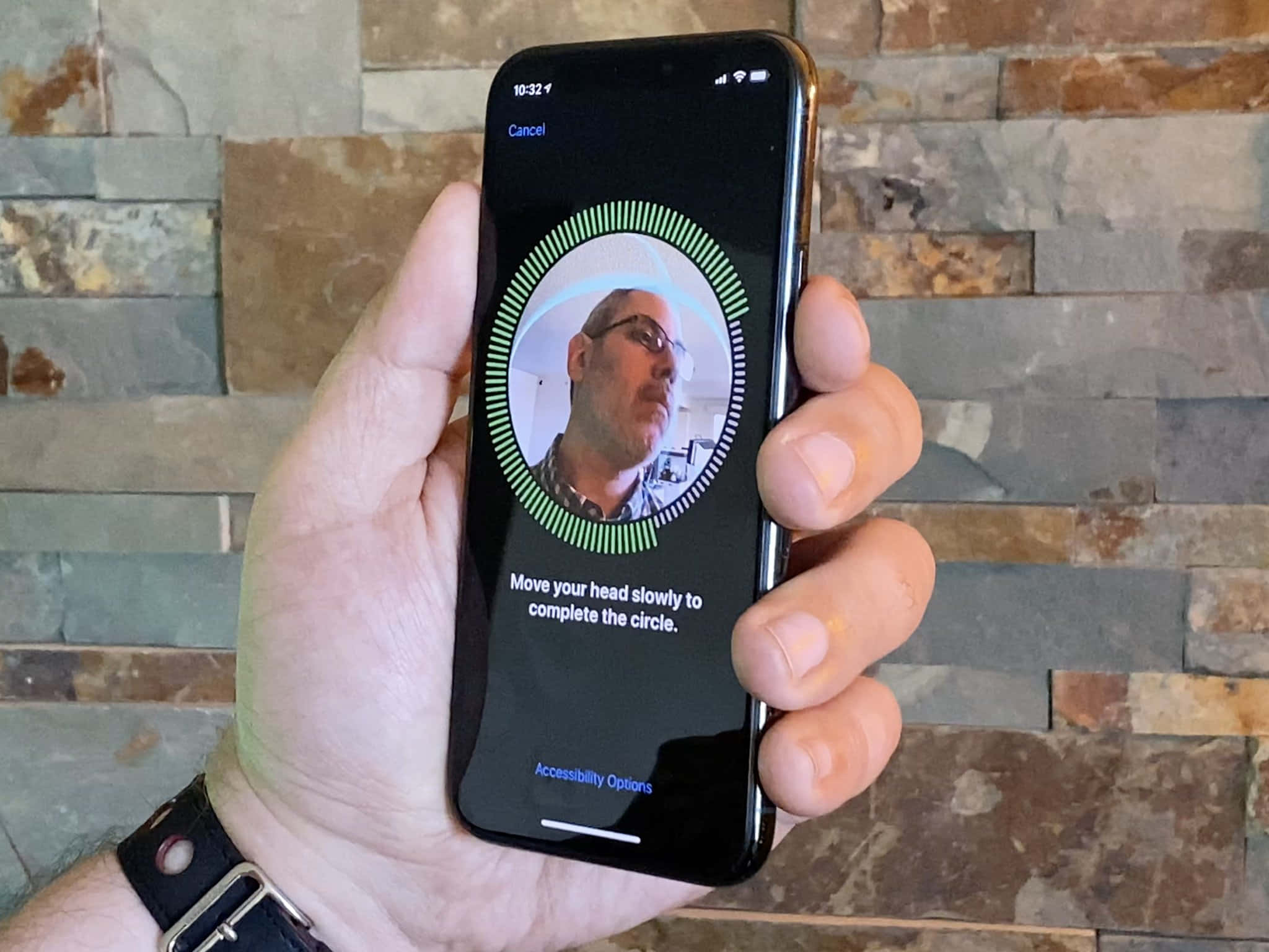 Face Id 桌布 壁紙 — 一隻手拿著智能手機，顯示面部識別設定畫面，背景為石牆。