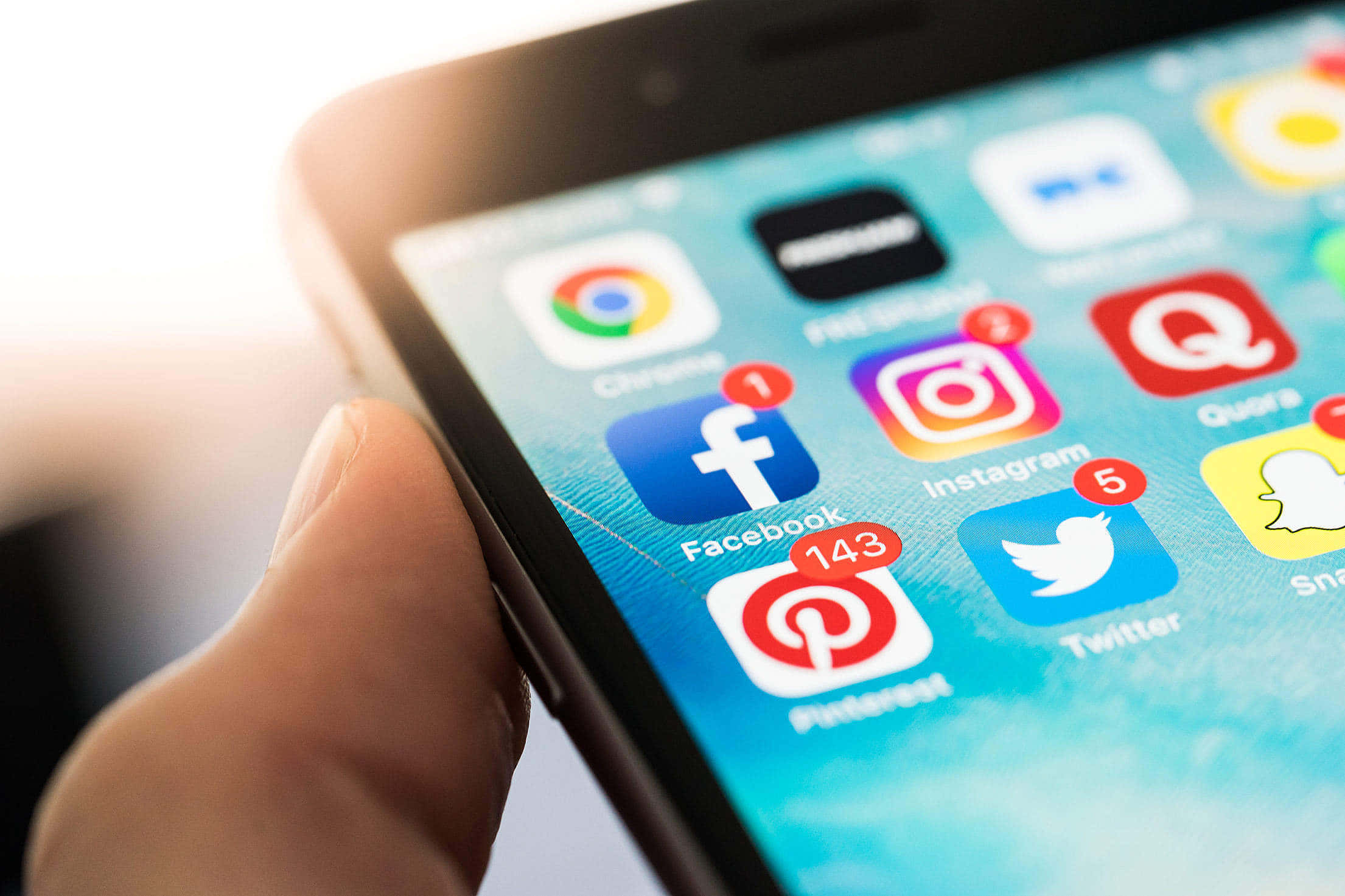 Social Media 桌布 壁紙 — 一隻手拿著智能手機的特寫，顯示社交媒體應用程式圖標和通知徽章。