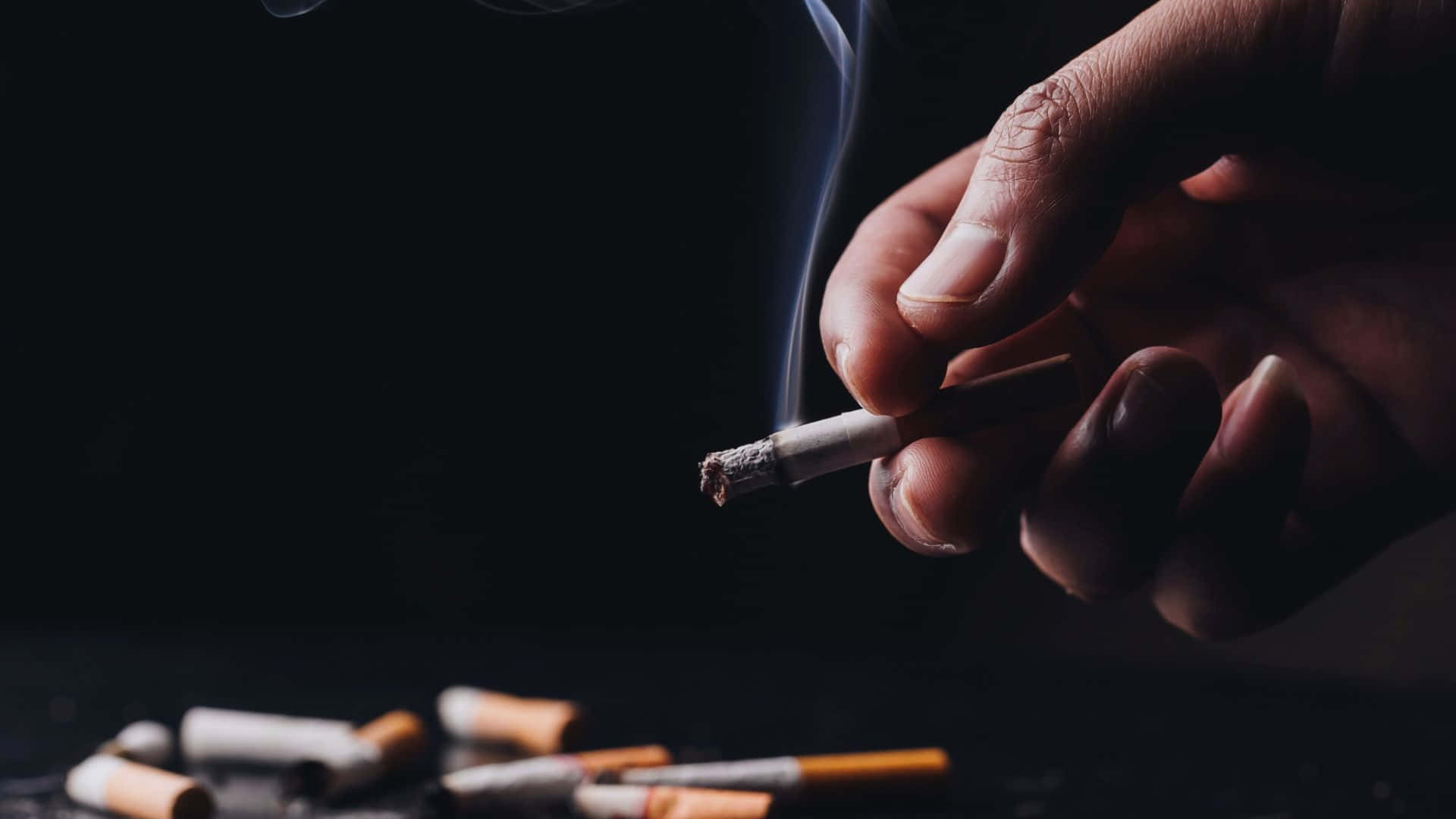 一隻手拿著香煙，煙霧裊裊升起 壁紙