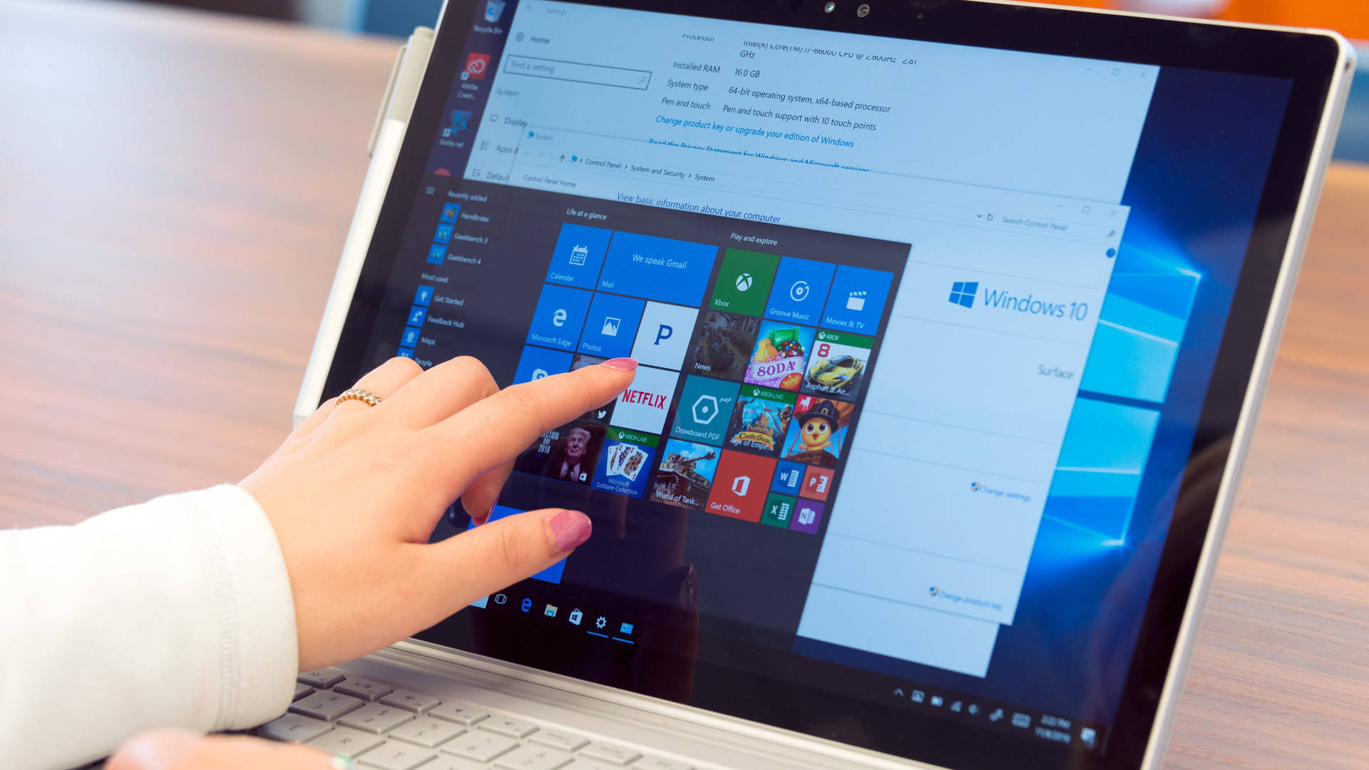 microsoft 桌布 壁紙 — 一隻手輕觸Windows 10平板電腦屏幕，顯示包含Netflix及其他方塊的應用程式網格。
