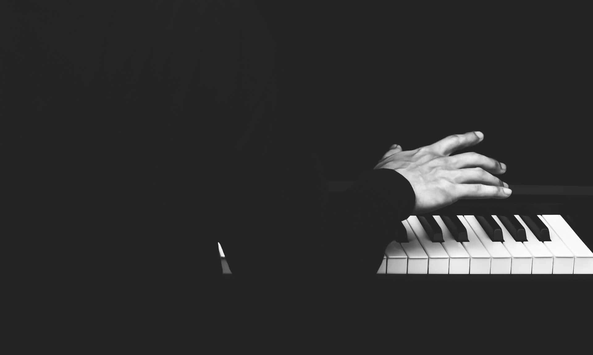 Black And White Piano 桌布 壁紙 — 一隻手輕輕放在鋼琴琴鍵上，在深色背景下呈現強烈的黑白對比。