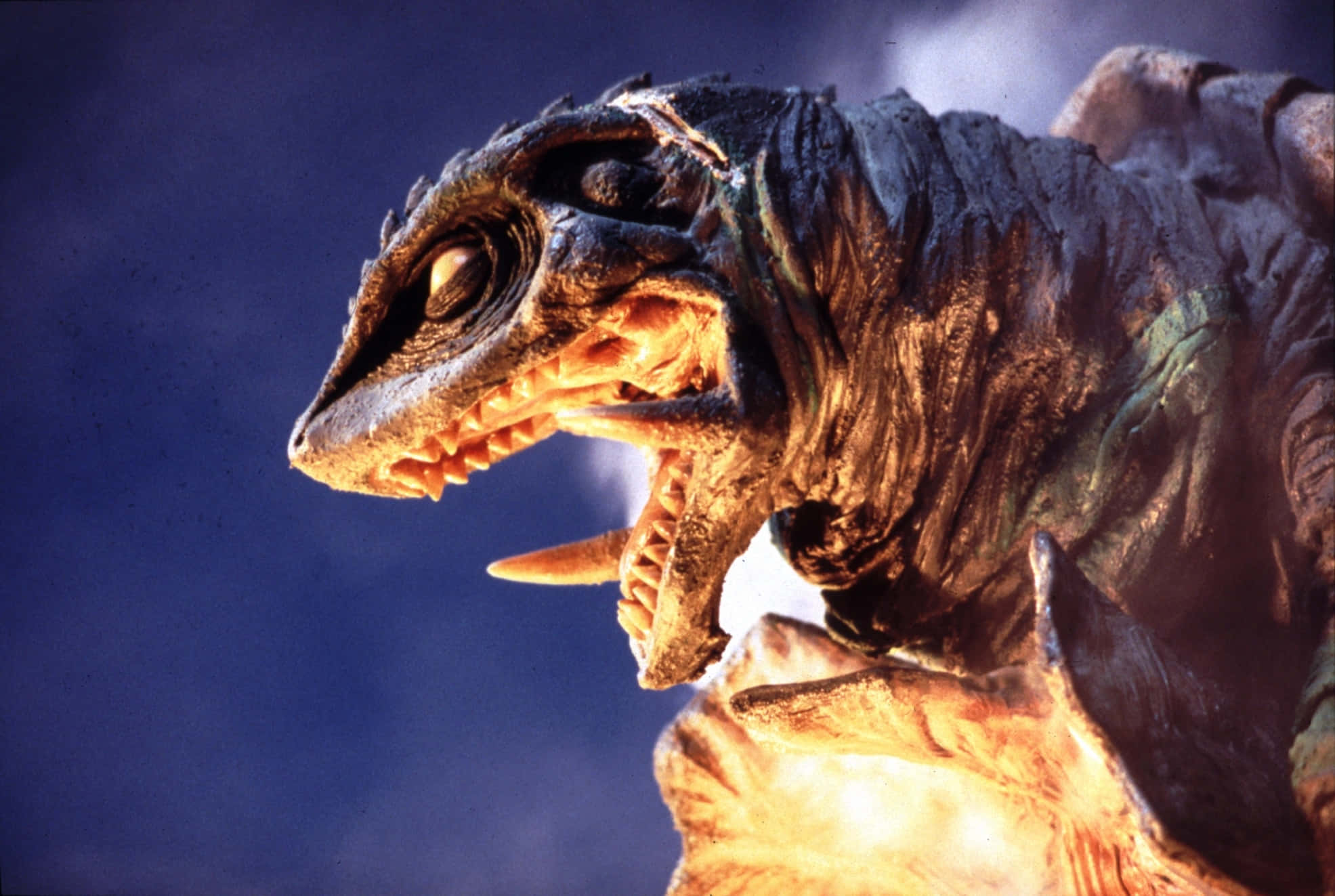 Gamera 桌布 壁紙 — 一隻擁有發光眼睛和鋒利牙齒的怪獸卡伊獸，在深藍色的天空下咆哮，胸口散發出火焰般的光芒。