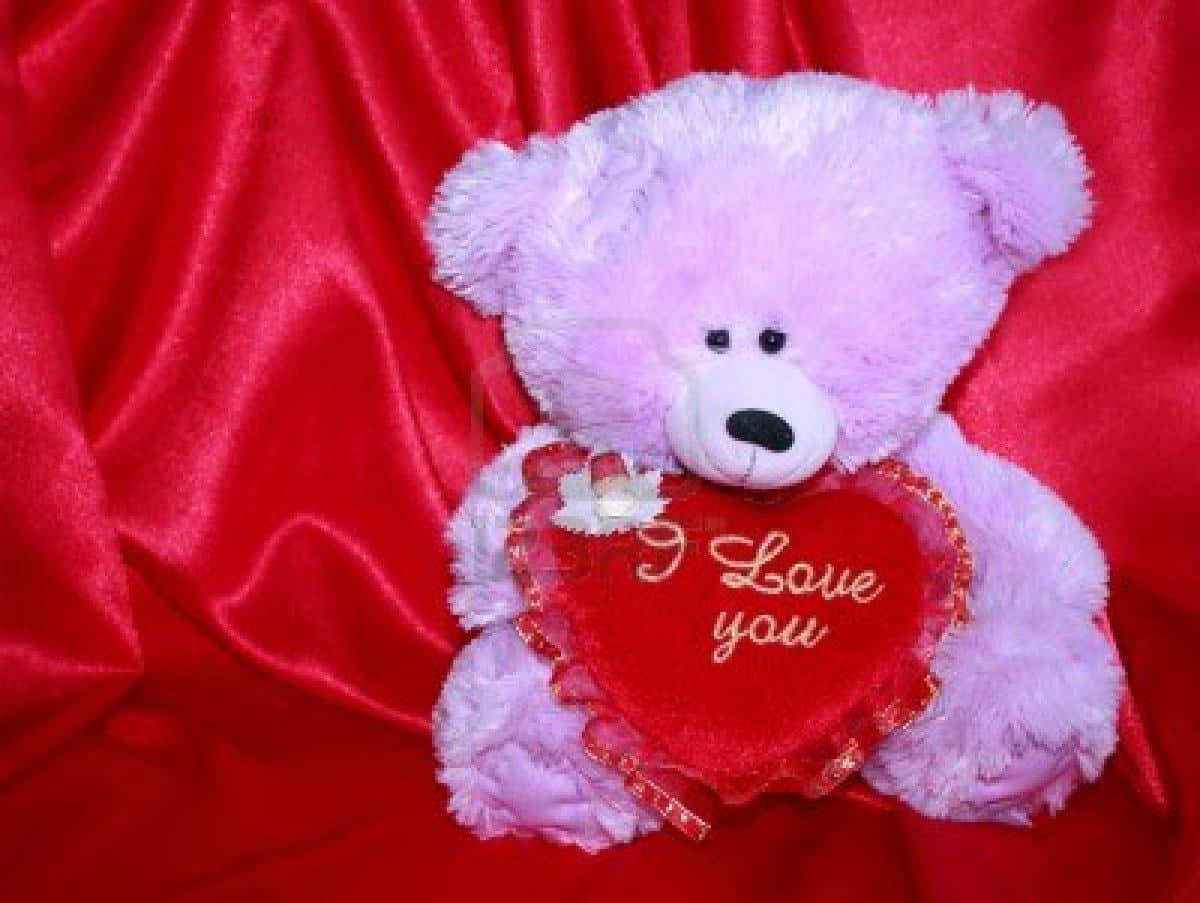 Teddy Bear 桌布 壁紙 — 一隻柔軟的薰衣草色泰迪熊抱著一個繡有「I Love You」的紅色心形，背景是濃郁的紅色緞面。