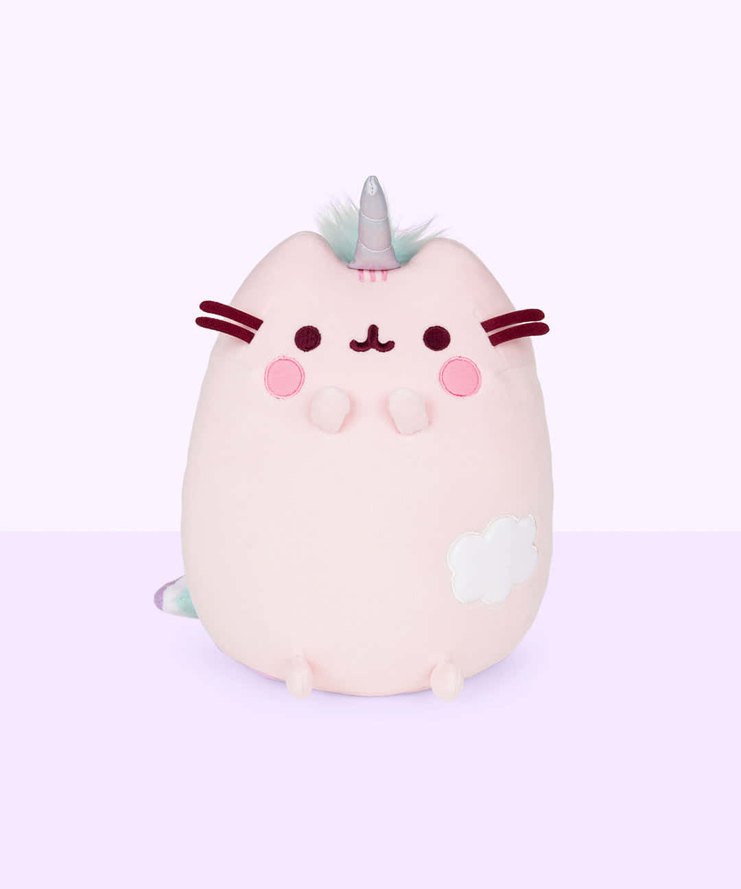 Pusheen 桌布 壁紙 — 一隻柔軟粉紅色毛絨獨角貓，帶有銀色角和雲朵補丁，坐在淡紫色背景前。