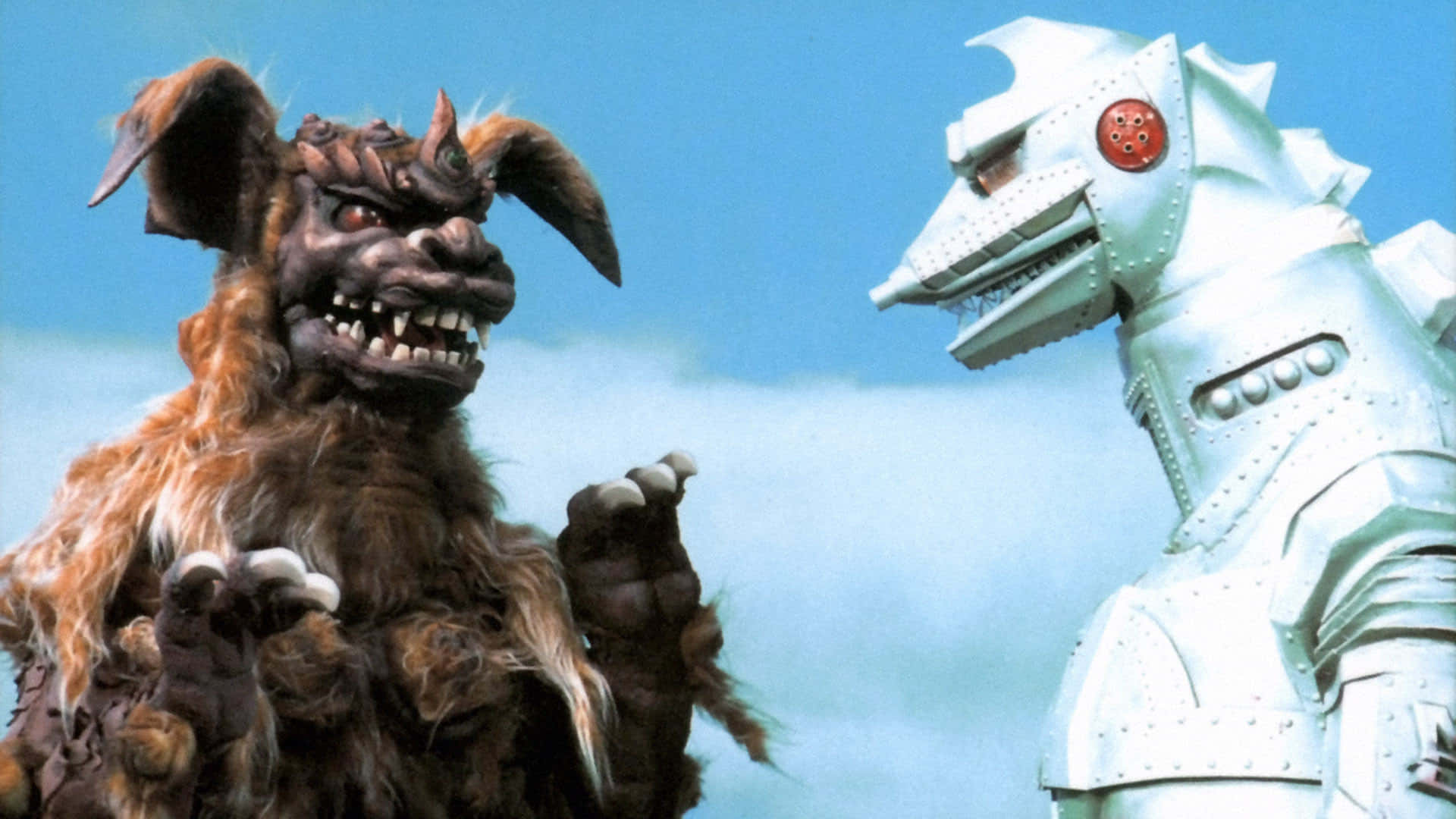 Robot Godzilla 桌布 壁紙 — 一隻毛茸茸的棕色怪物，長著鋒利的牙齒，在晴朗的藍天下與銀色裝甲機器人對峙。