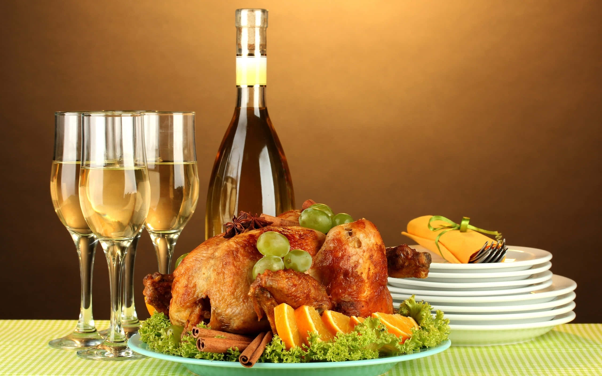 Food And Beverage 桌布 壁紙 — 一隻烤火雞，飾以葡萄、橙子和肉桂，放在托盤上，旁邊有香檳杯和一瓶酒，背景是溫暖的棕色。
