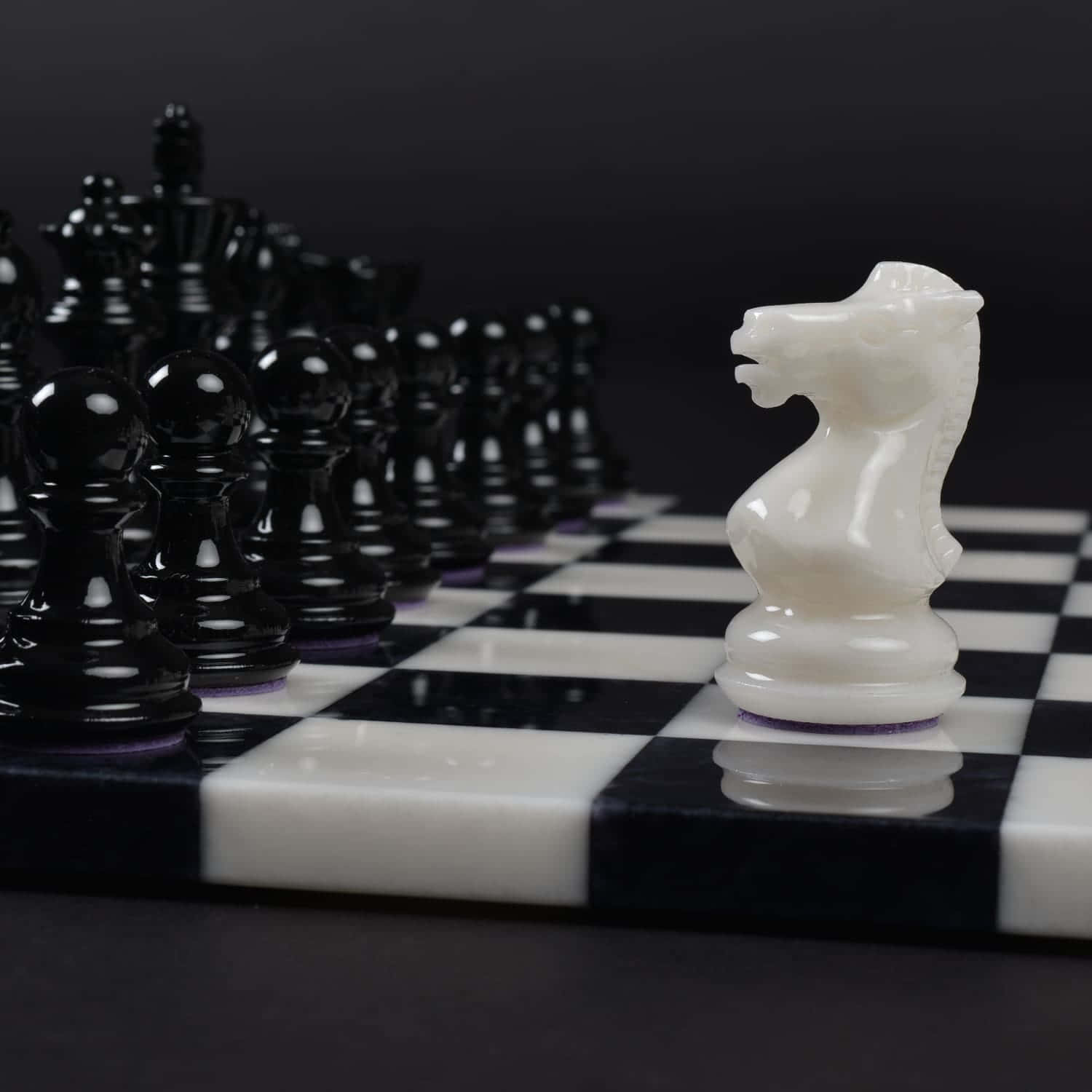 Black And White Chess 桌布 壁紙 — 一隻白色國際象棋騎士站在棋盤上，面對著一群黑色棋子，形成戲劇性的對峙。
