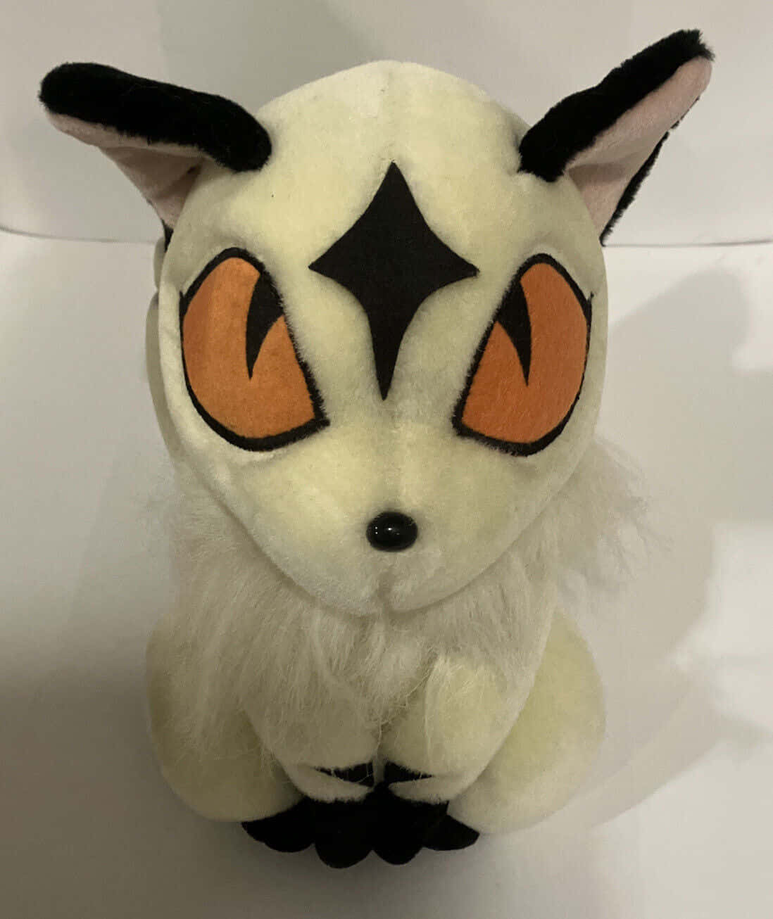 Inuyasha Nekomata 桌布 壁紙 — 一隻白色毛髮、黑色斑紋和橙色眼睛的寶可夢阿勃梭魯毛絨玩具，直立在純白色背景前。