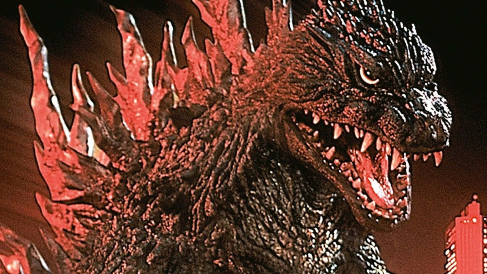 Godzilla 2000 桌布 壁紙 — 一隻眼睛發光、背鰭火紅的怪獸哥斯拉，在黑暗的城市天際線前發出威脅性的咆哮。