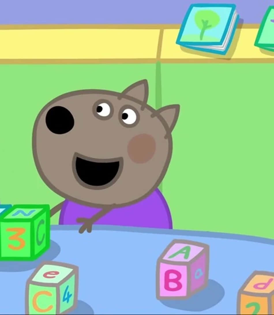 Danny Dog 桌布 壁紙 — 一隻穿著紫色襯衫的開心卡通狐狸，在藍色桌子上玩色彩繽紛的字母和數字積木，面帶微笑。