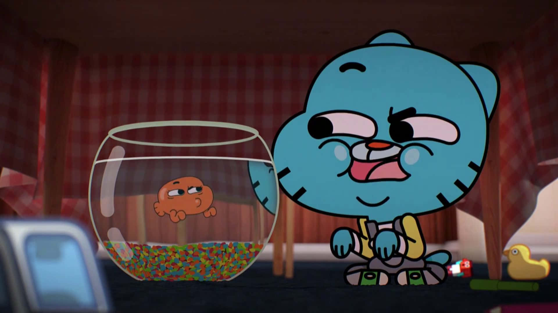 Gumball And Darwin 桌布 壁紙 — 一隻藍色卡通貓咪帶著得意的表情坐在一個裝有一條小橙色魚和彩色礫石的魚缸旁邊。