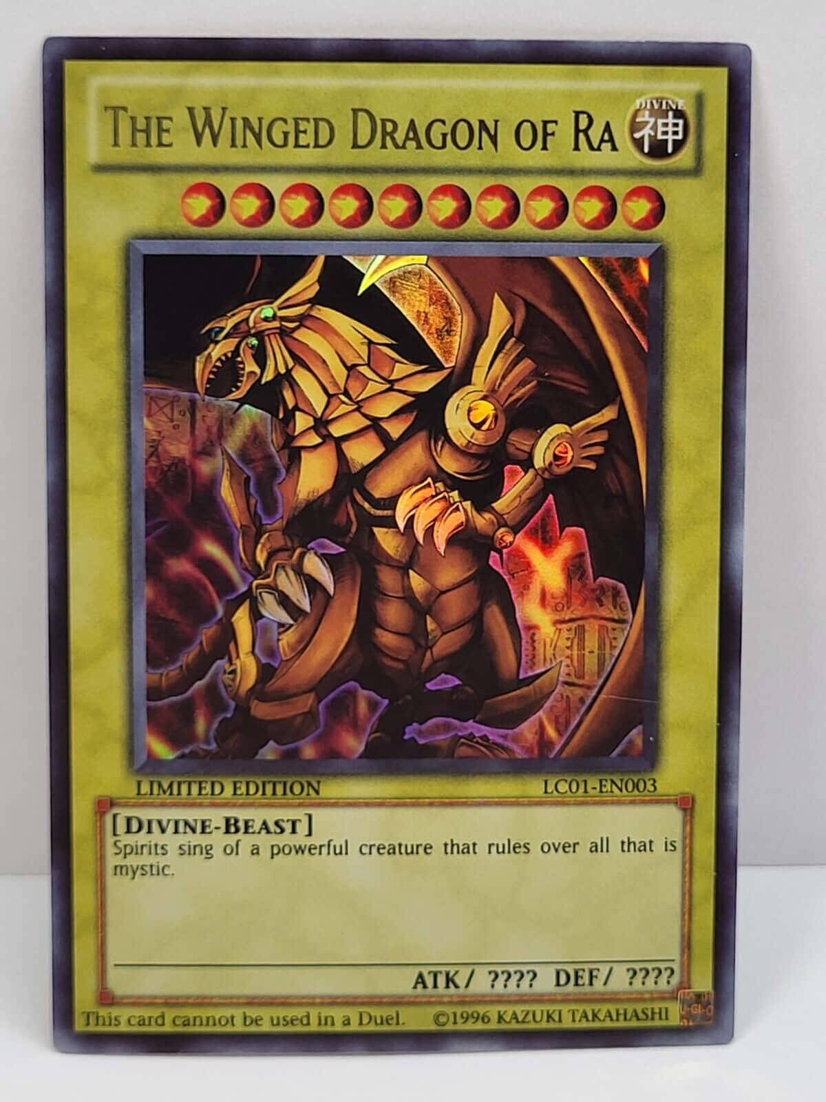 The Winged Dragon Of Ra 桌布 壁紙 — 一隻金色有翼的龍，眼睛發光，翅膀燃燒，在黑暗神秘背景的遊戲王集換式卡牌上咆哮。