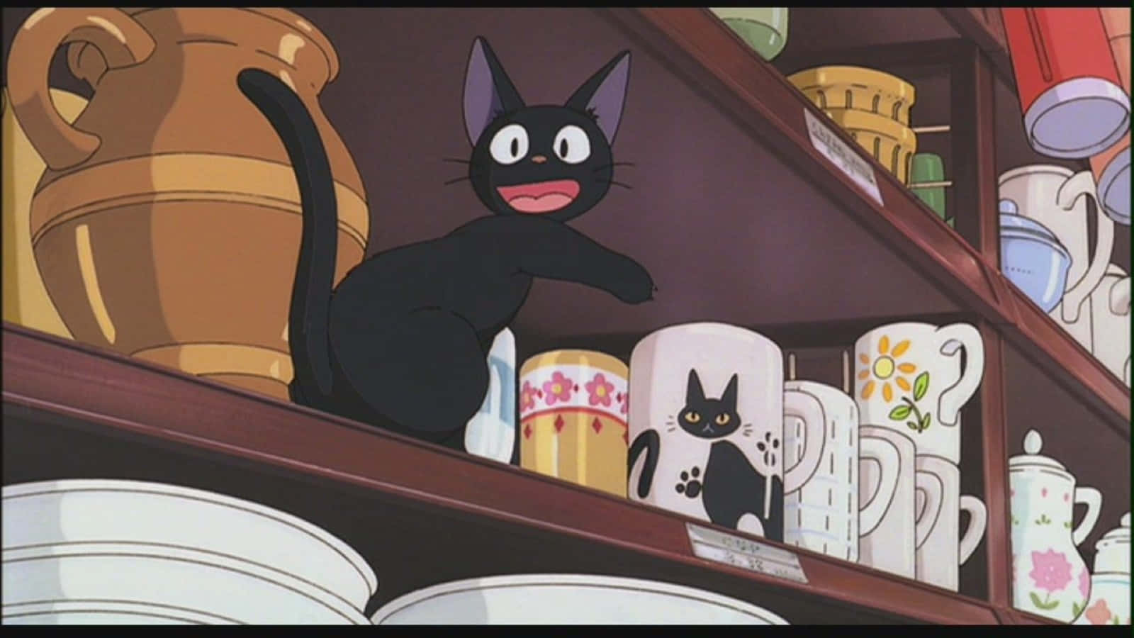 Jiji Cat 桌布 壁紙 — 一隻開心的大眼睛黑貓棲息在木架上，周圍是色彩繽紛的杯子和陶器。