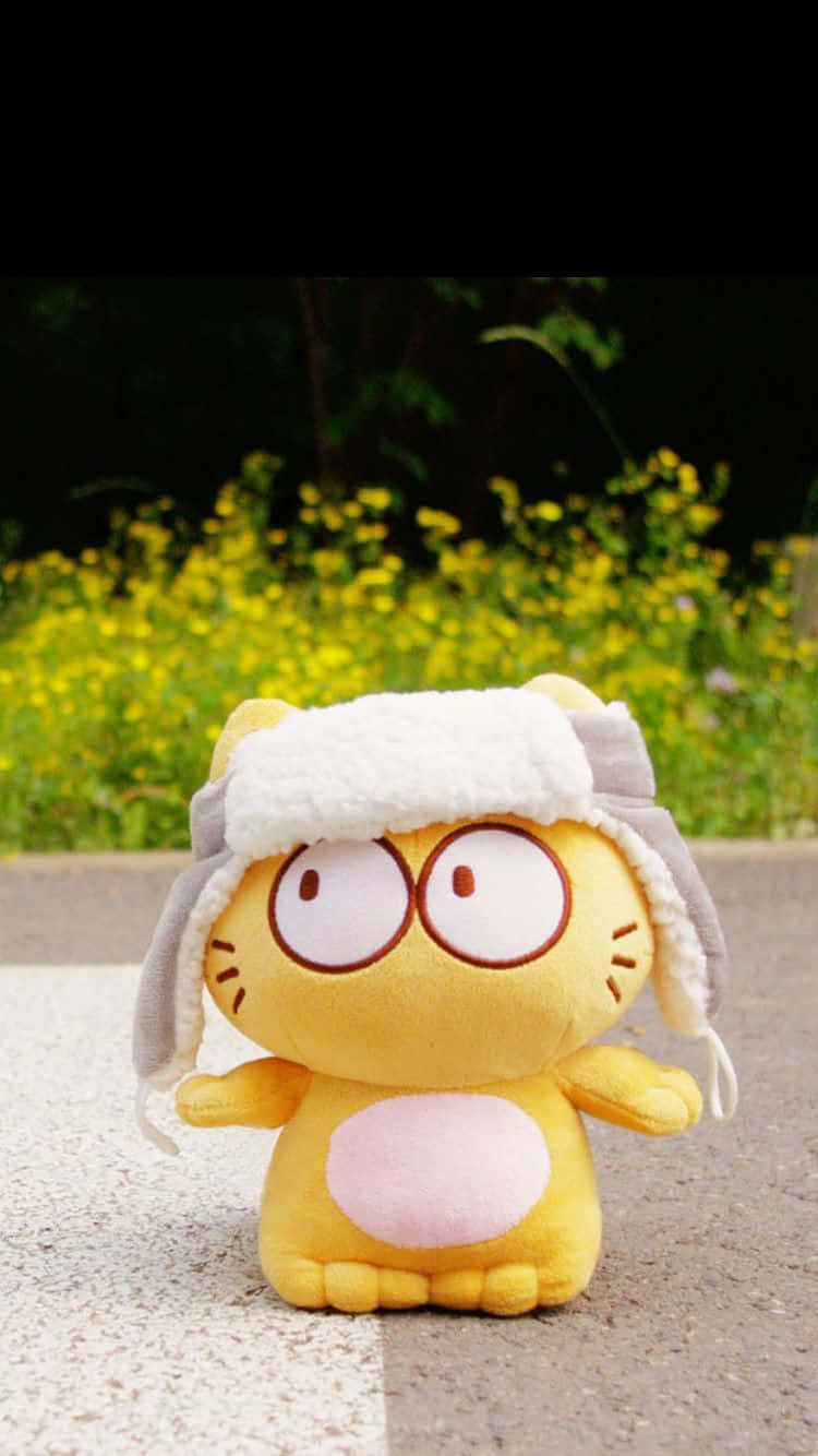 Cute HD 桌布 壁紙 — 一隻黃色毛絨貓戴著白色蓬鬆帽子坐在行人路上，後面是一片黃色花田。