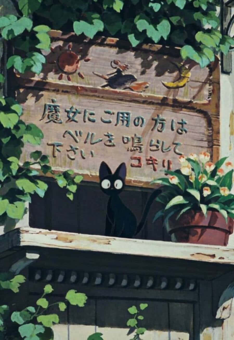 Jiji Cat 桌布 壁紙 — 一隻黑貓睜大眼睛，從一個帶有日文字句及太陽、月亮、雀鳥插圖的木牌後面探頭出來，周圍是茂密的綠葉和一盆花卉。