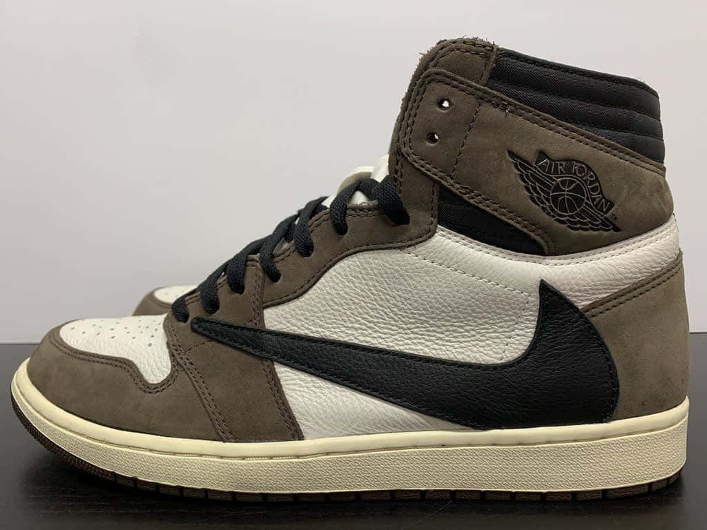 Travis Scott Jordan 1 桌布 壁紙 — 一雙高筒Air Jordan運動鞋，採用大地棕色、白色和黑色皮革，搭配奶油色鞋底，放置在深色表面上，背景簡潔。
