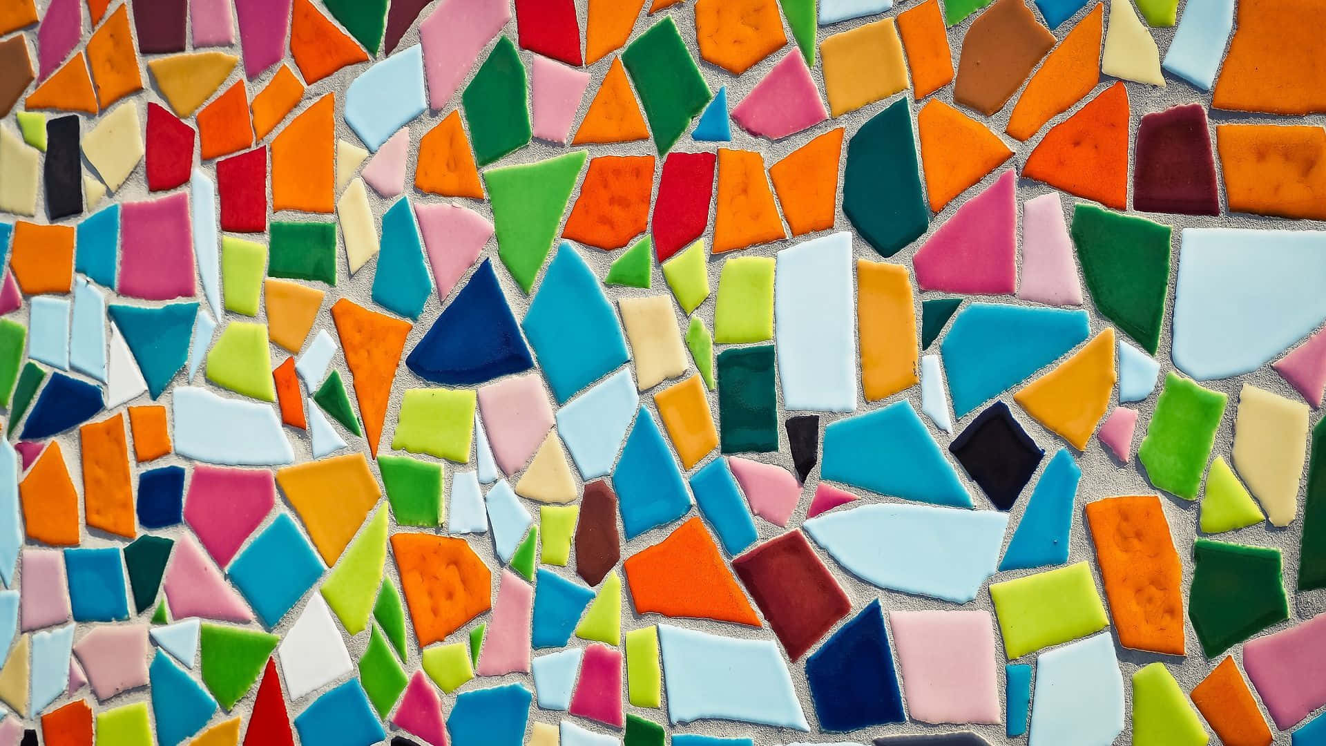 Mosaic 桌布 壁紙 — 一面充滿活力的馬賽克牆，由不規則形狀的彩色陶瓷磚組成，採用大膽的橙、粉紅、藍、綠和白色調。