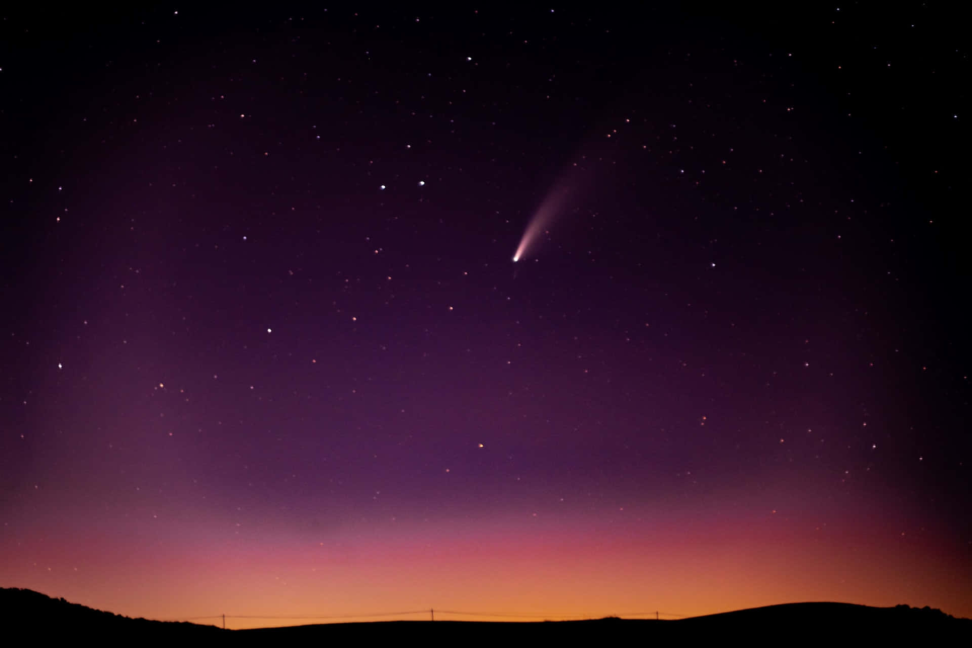 comet 桌布 壁紙 — 一顆彗星劃過繁星點點的暮色天空，下方是帶有紫色和橙色漸變的剪影山丘。