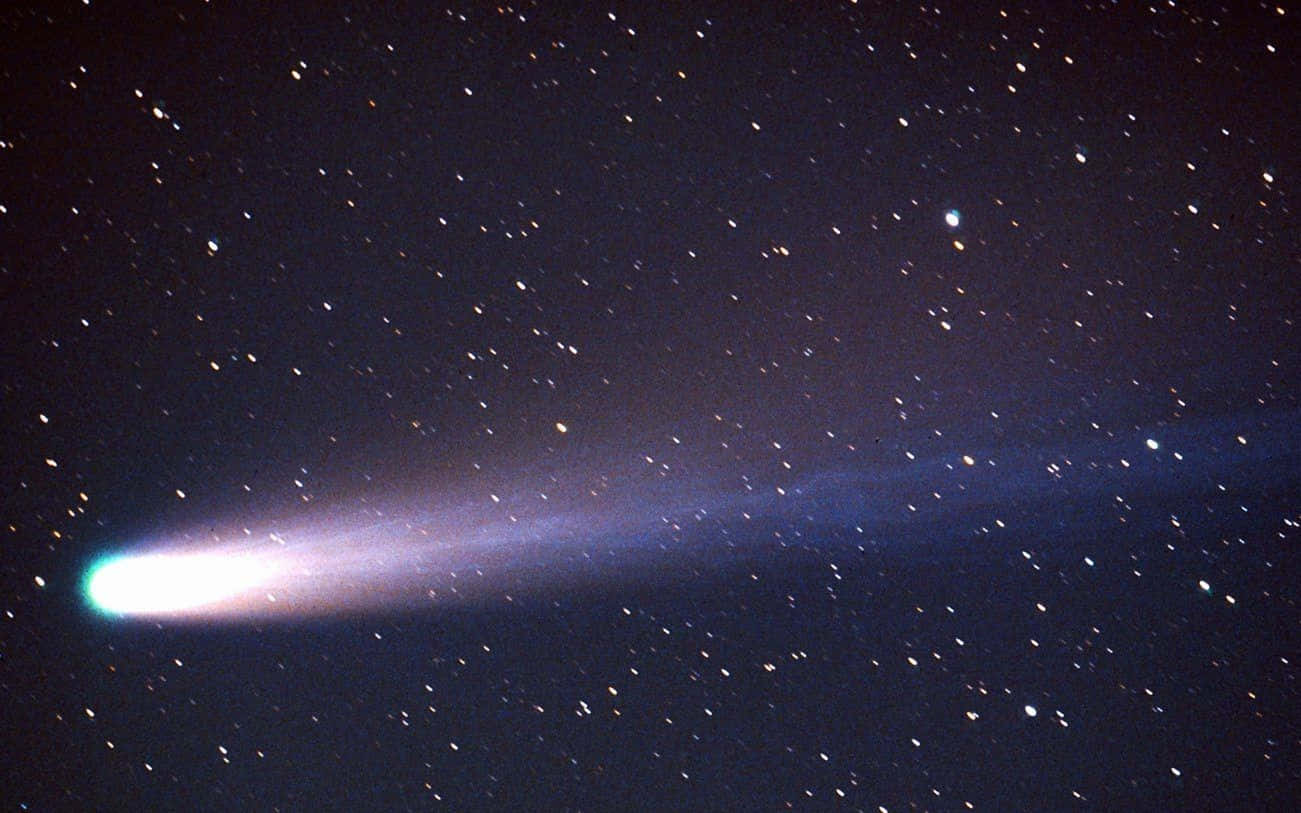 comet 桌布 壁紙 — 一顆明亮的彗星劃過繁星點點的夜空，留下一條發光的藍白色尾巴。