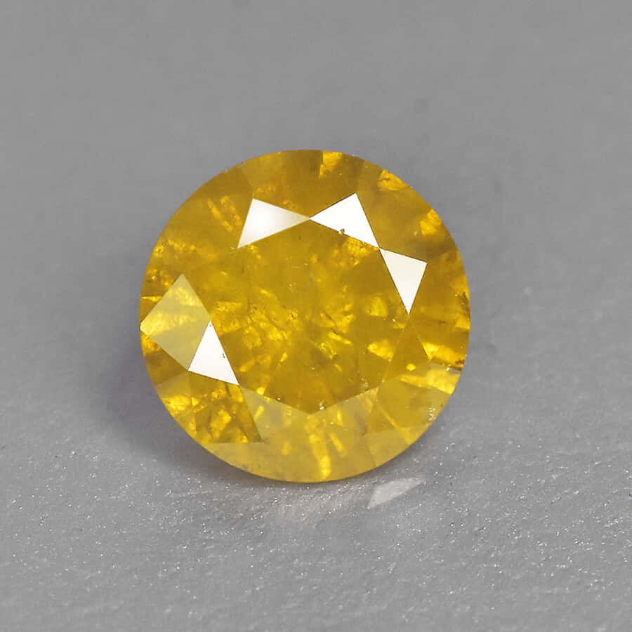 Yellow Diamond 桌布 壁紙 — 一顆明亮的黃色圓形切割寶石，在灰色紋理表面上閃耀著刻面。