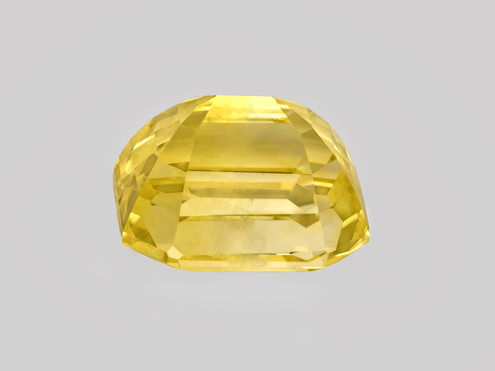 Yellow Sapphire 桌布 壁紙 — 一顆璀璨的黃色枕形切割寶石，在柔和的灰色背景下閃耀著精準的刻面。
