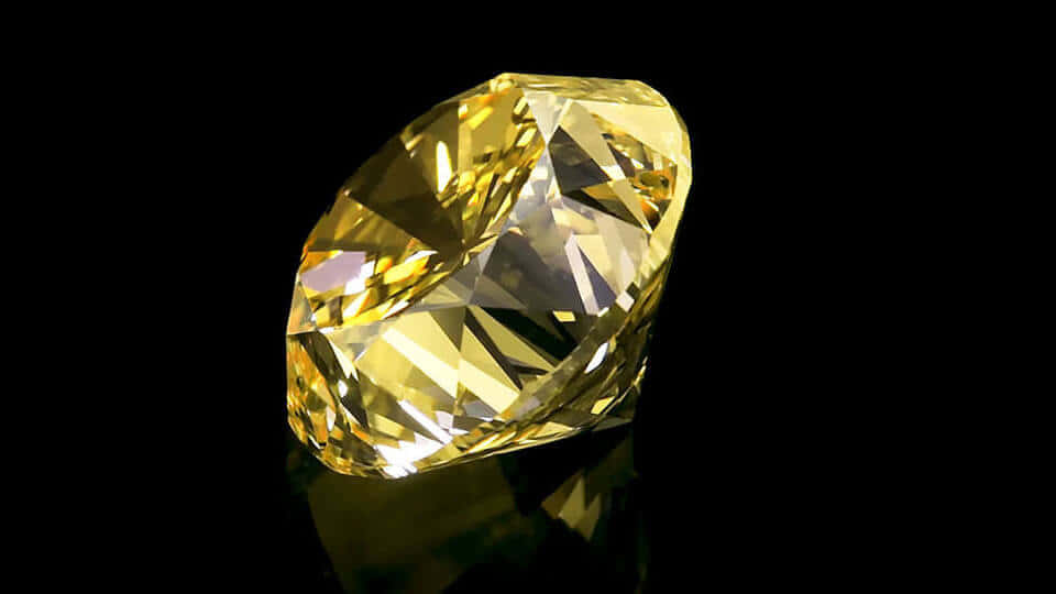 Yellow Diamond 桌布 壁紙 — 一顆璀璨的黃鑽在純黑背景上閃耀著銳利的切面，投射出微妙的倒影。