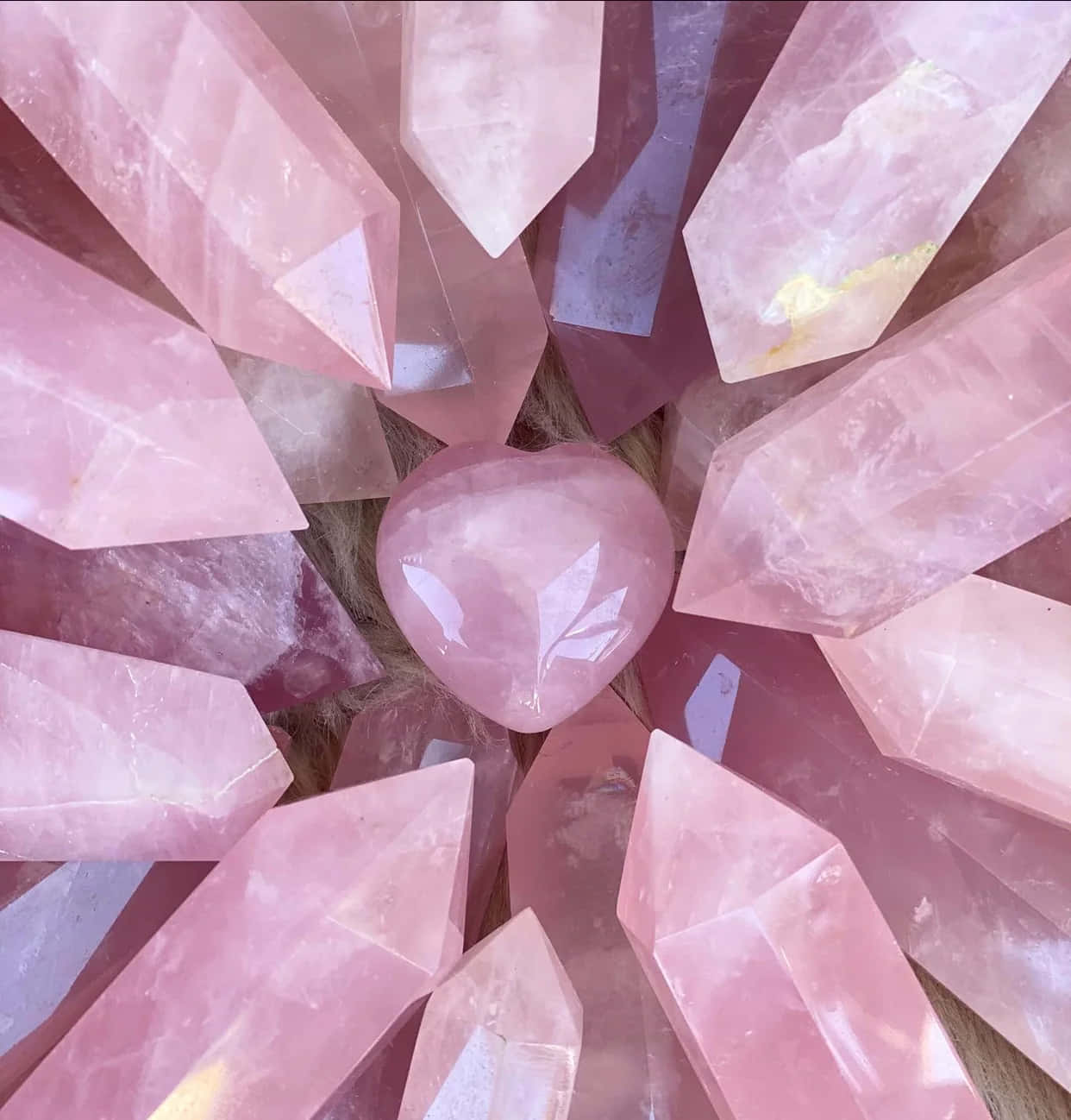Pink Crystal Quartz 桌布 壁紙 — 一顆閃耀的心形玫瑰石英，鑲嵌在柔軟紋理表面上的幾何粉紅水晶尖點之間。